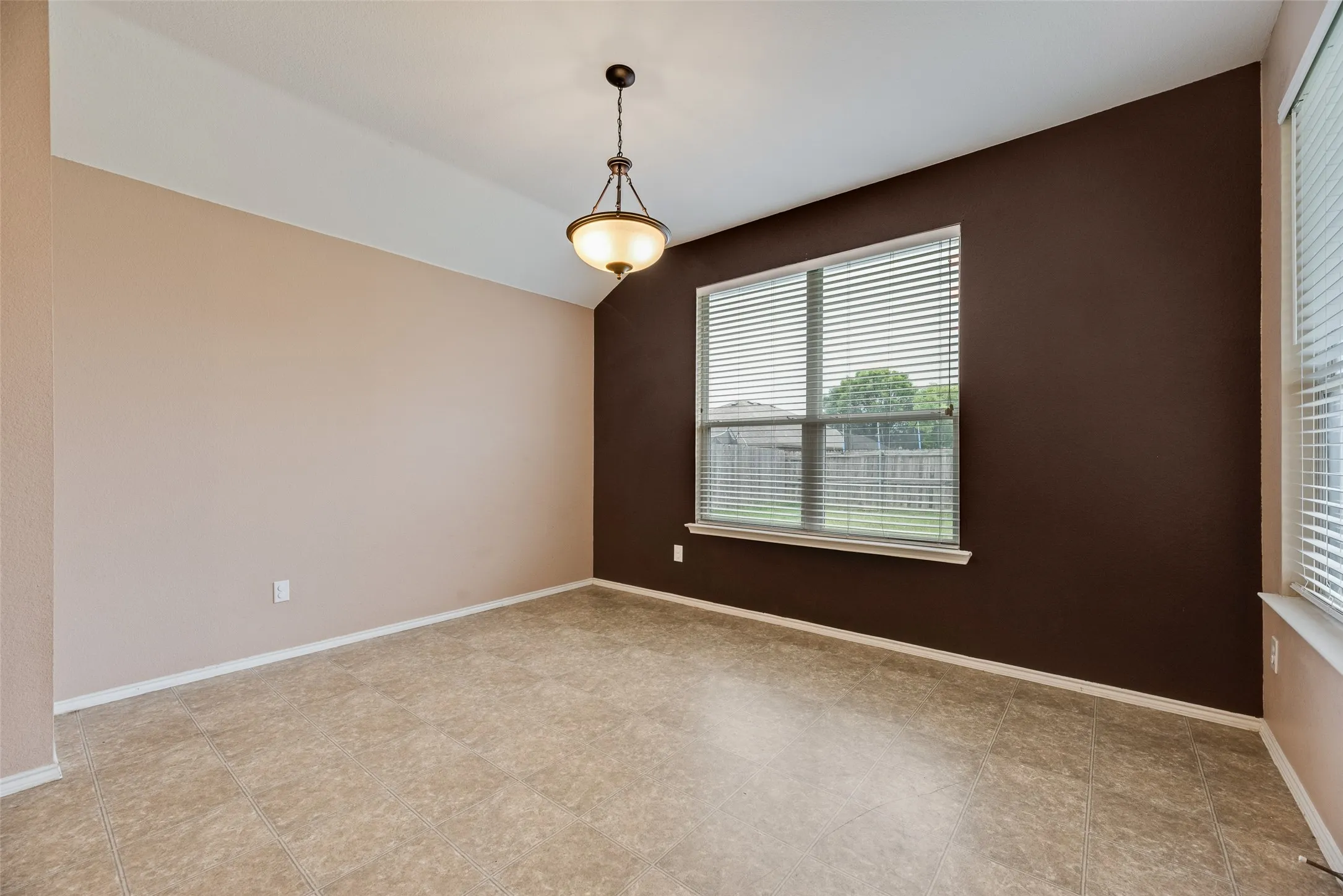 Room featuring warm beige and dark brown walls, a tiered ceiling, and tiled flooring