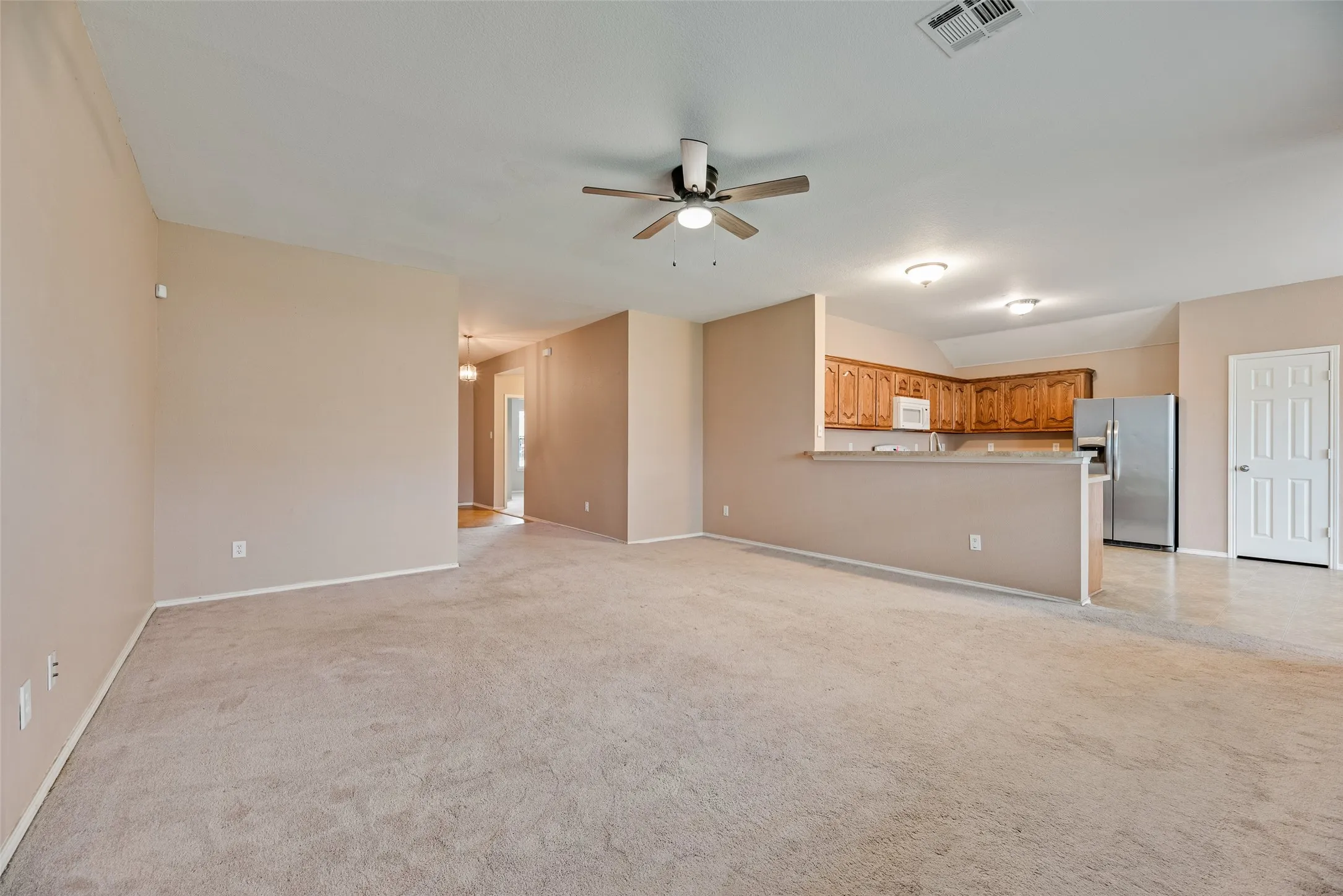 Spacious living area featuring neutral carpeting and wall tones