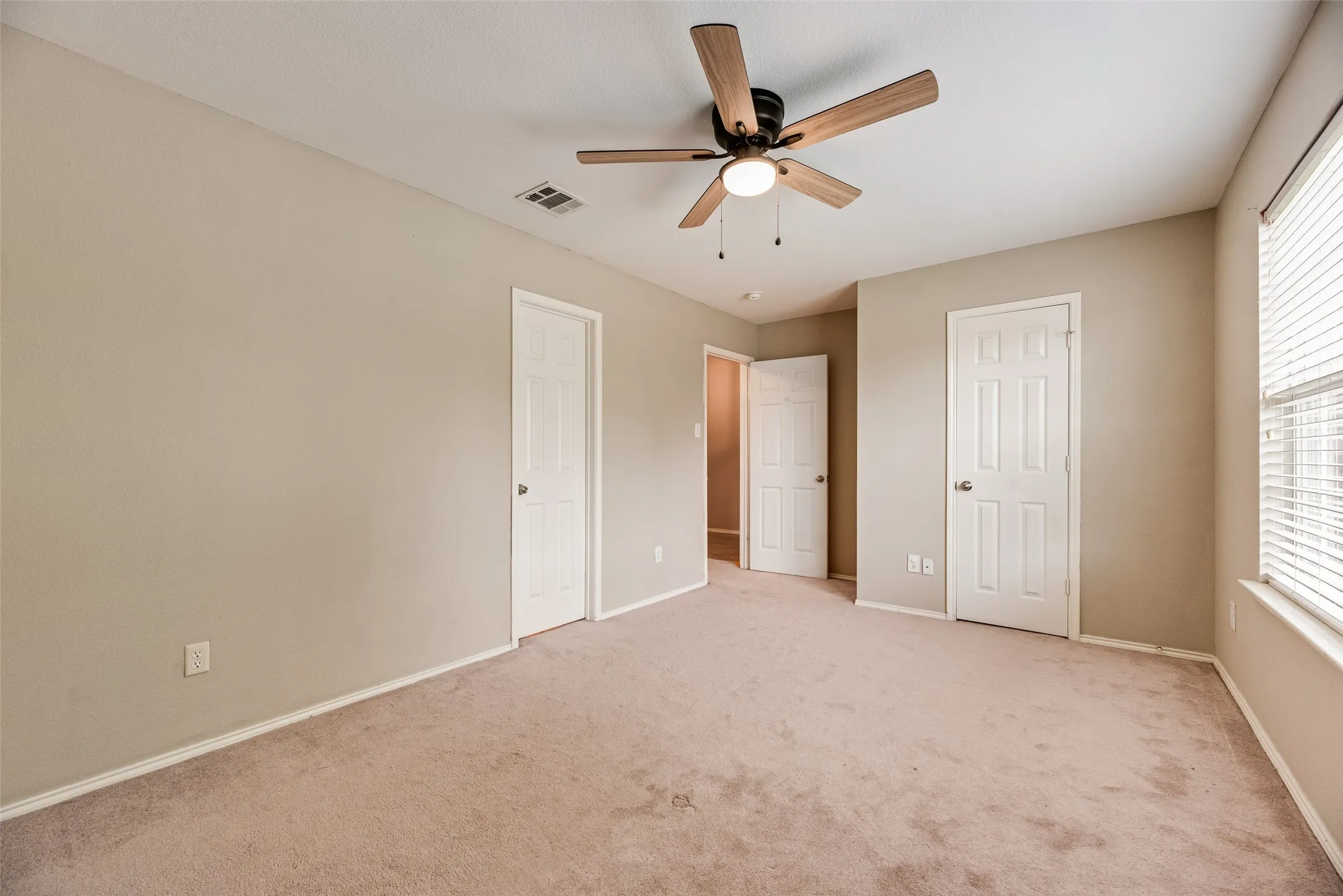 Carpeted room featuring neutral-toned walls, white trim, and multiple white paneled doors
