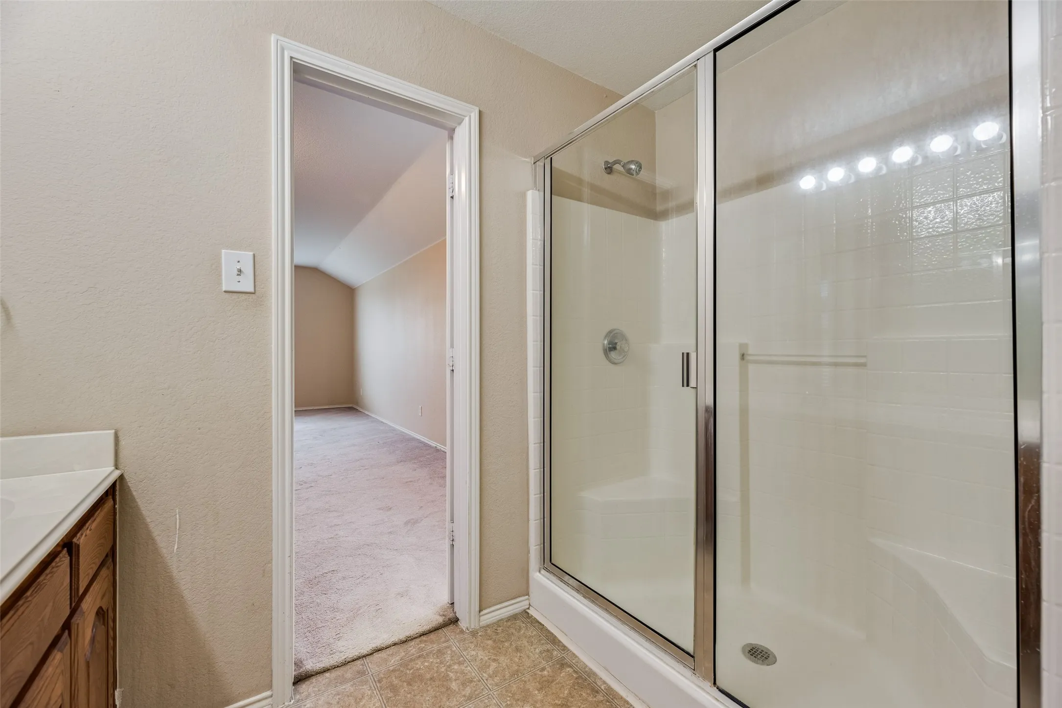Shower enclosure with clear glass doors and chrome framing, featuring a built-in seat and integrated shelving
