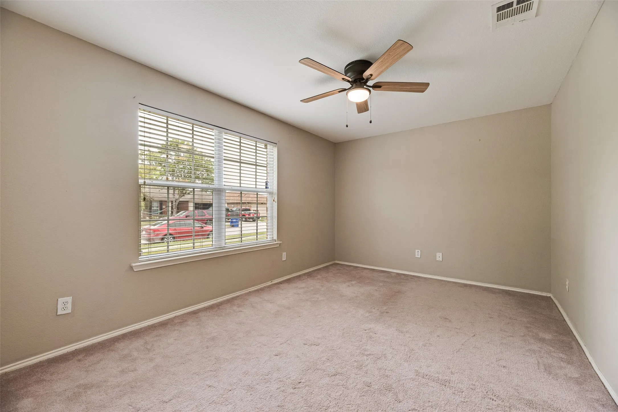 Carpeted interior space featuring a ceiling fan with integrated lighting, a single window with blinds, and neutral-toned walls