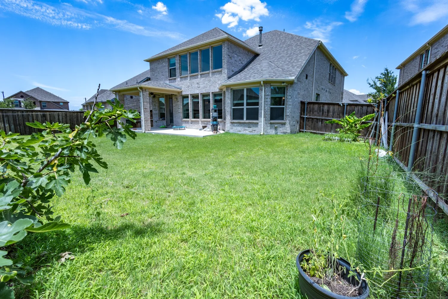 Spacious backyard with a large lawn, privacy fencing, and a concrete patio