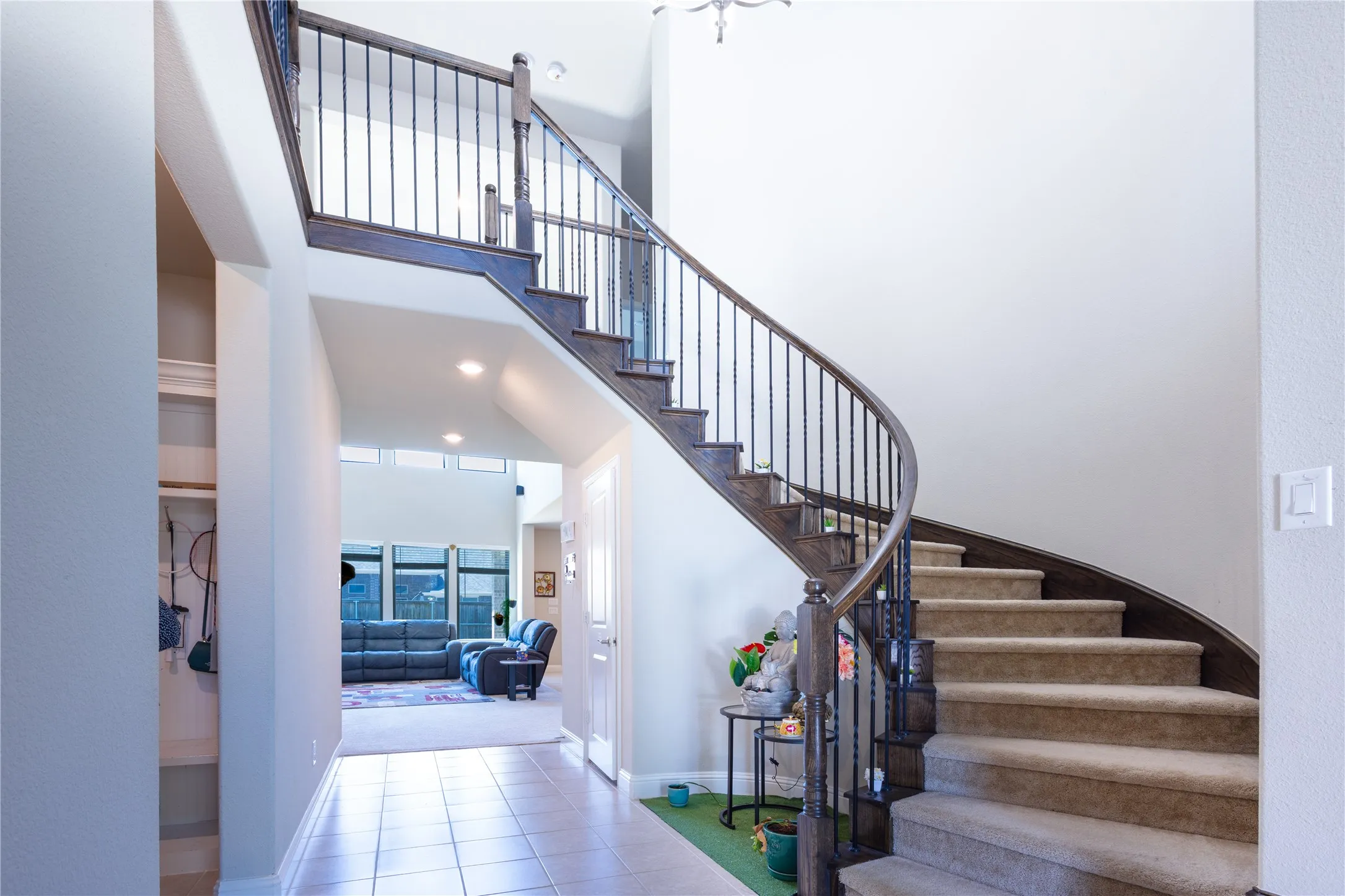 Grand curved staircase with wrought iron balusters and dark wood handrails