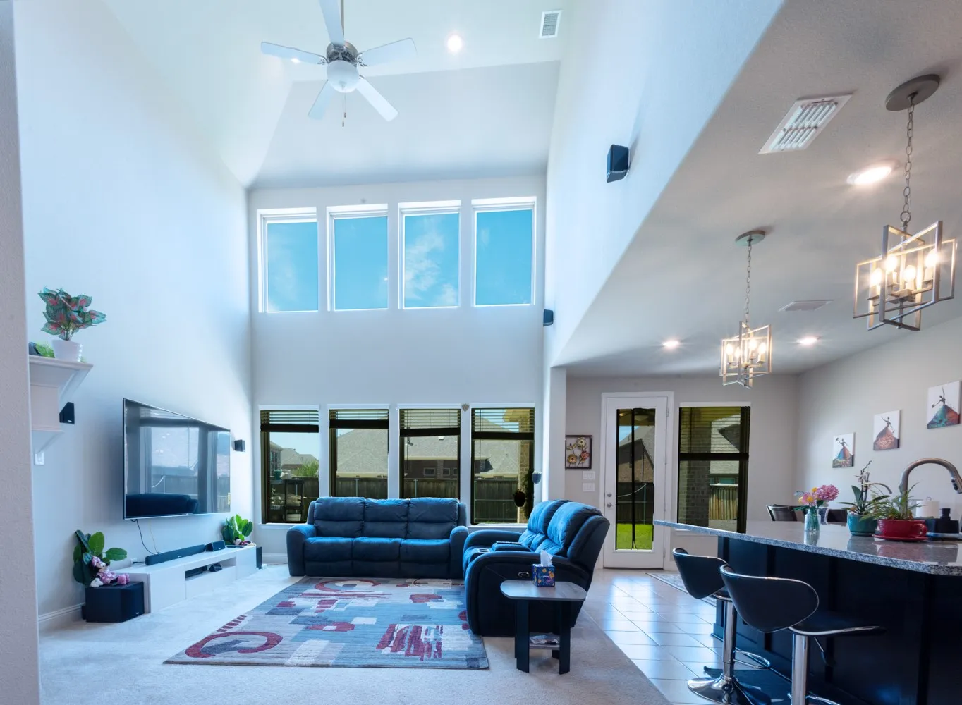 Open-concept living space featuring a soaring vaulted ceiling, an array of upper and lower windows, and a ceiling fan