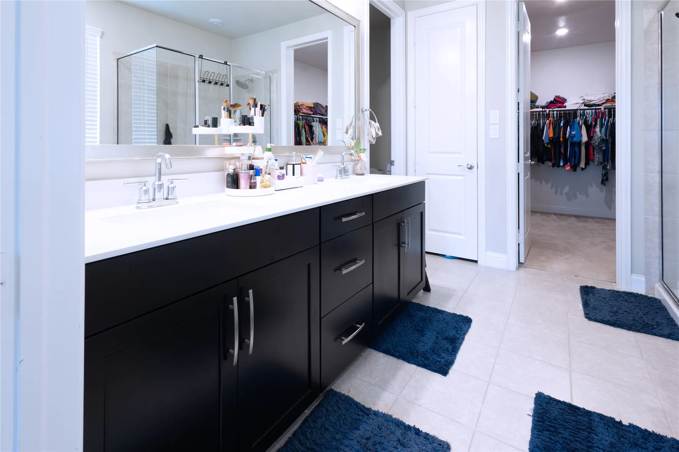 Double vanity featuring dark wood cabinetry, integrated sinks, chrome fixtures, and a spacious mirrored wall