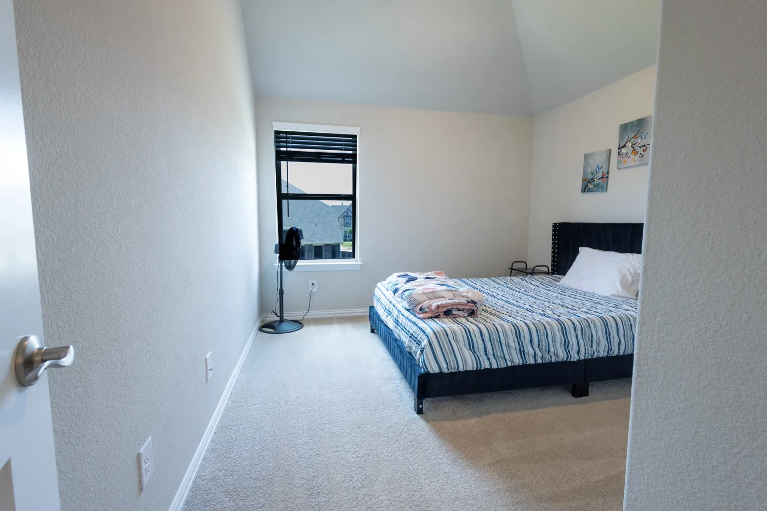 Carpeted room featuring a single window with blinds, vaulted ceiling, and white baseboards