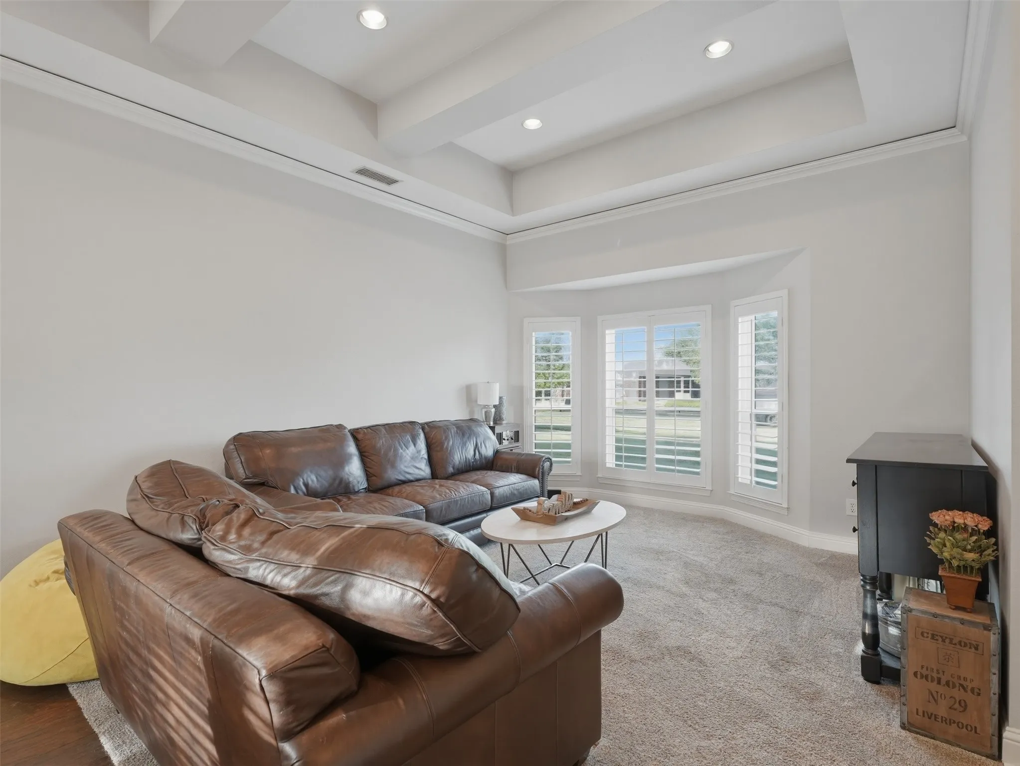 Bright formal living space featuring a tray ceiling with recessed lighting