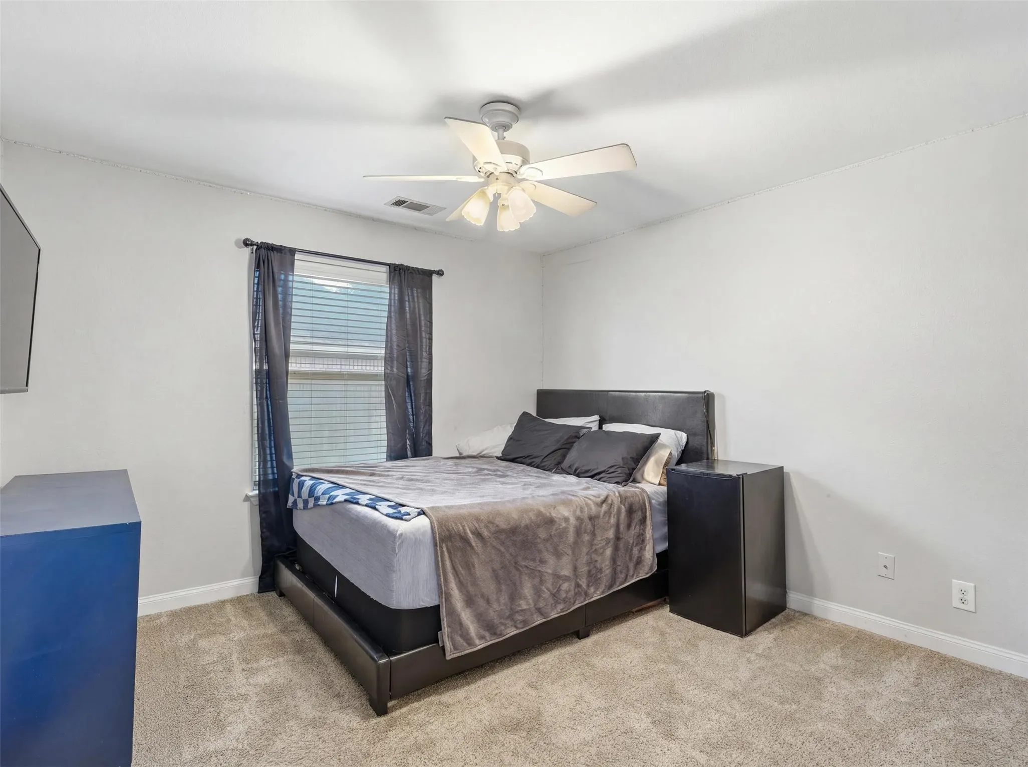 Carpeted room featuring a ceiling fan with integrated lighting, a window with blinds, and white baseboards