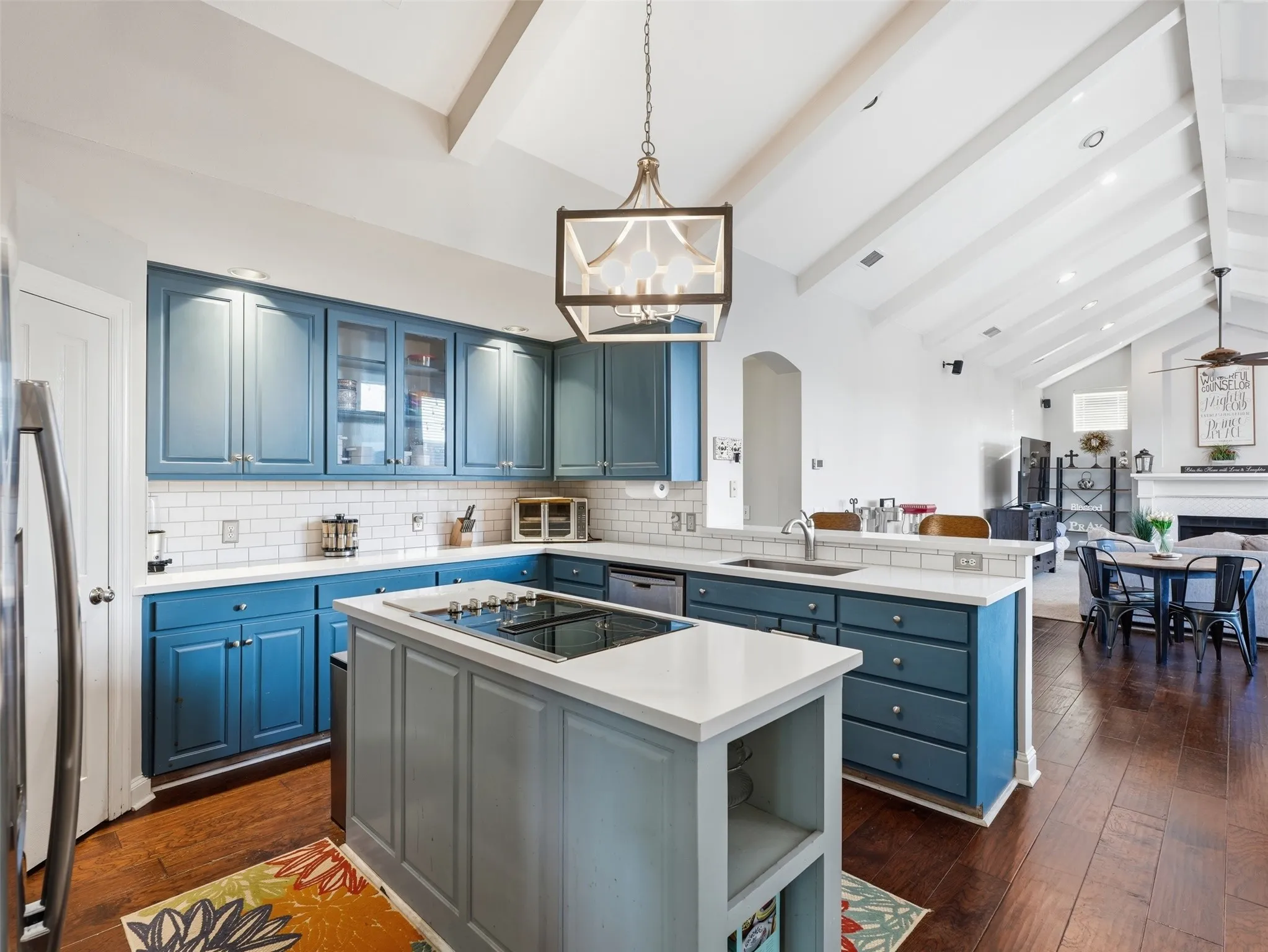 Kitchen featuring blue cabinetry, white countertops, subway tile backsplash, and a central island with a cooktop