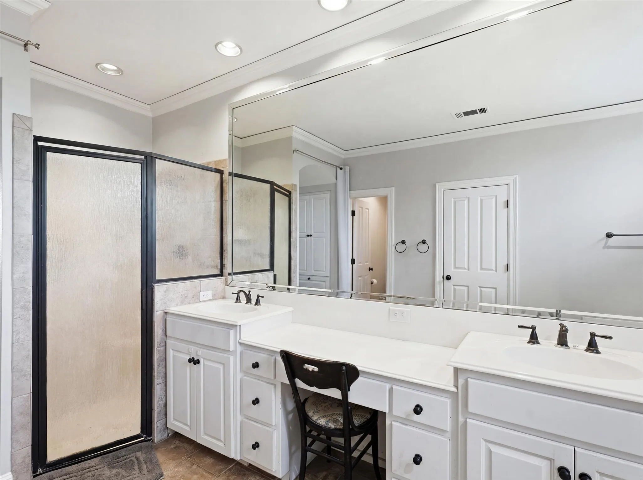 Bathroom featuring dual vanity sinks set in white cabinetry with a built-in makeup vanity