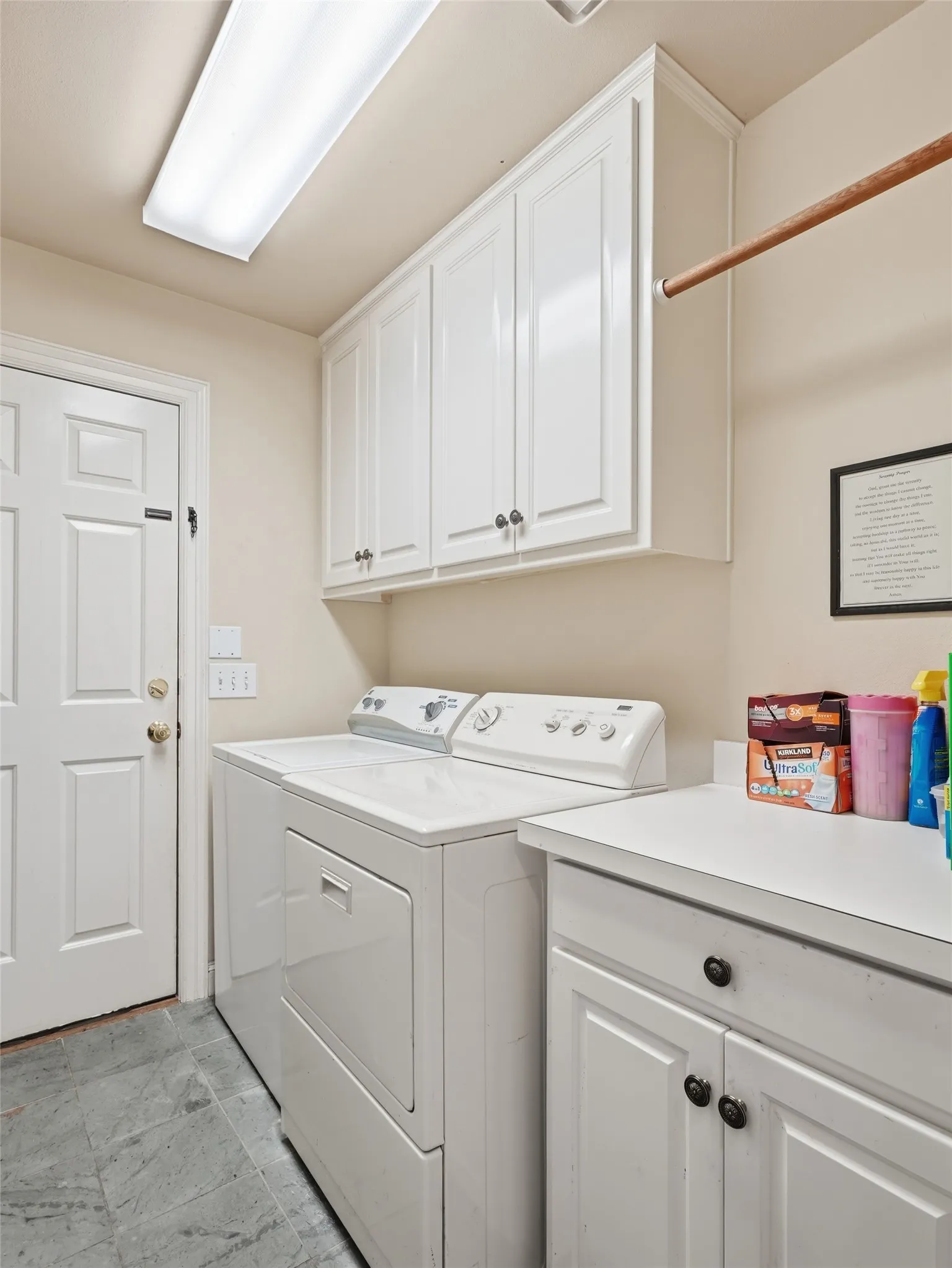 Utility room featuring extensive white cabinetry, a built-in counter, and stone-finish flooring