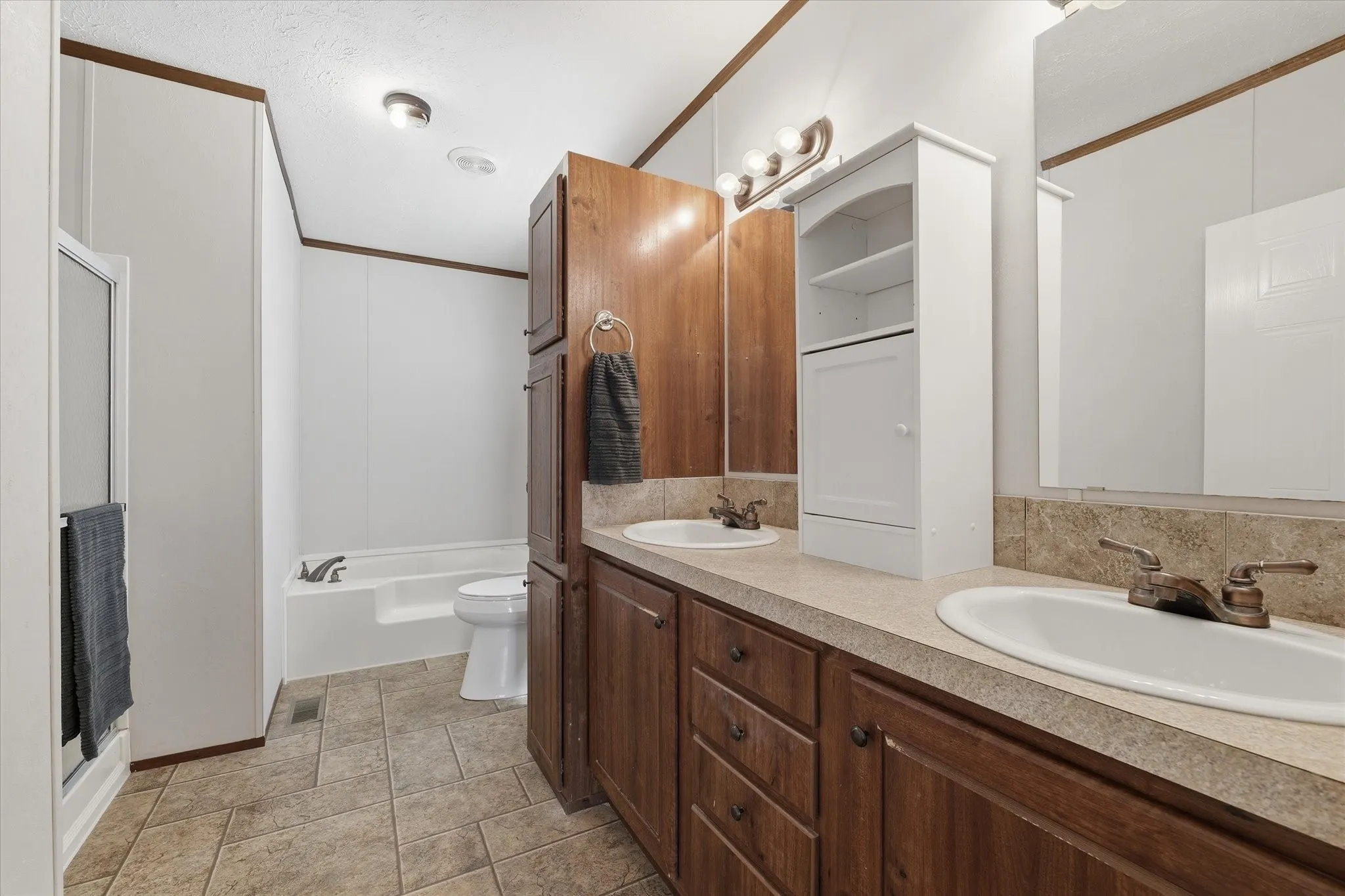 Primary bath has dual vanities, a walk-in shower, and a garden tub.