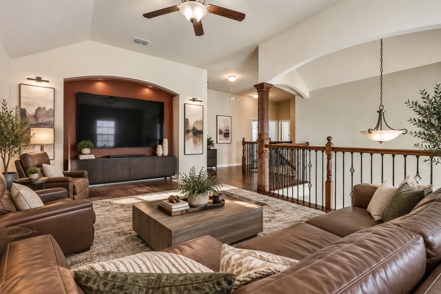 Arched media niche with recessed lighting, wood-finish flooring, high vaulted ceilings, and a decorative staircase with wood newel posts and wrought iron balusters