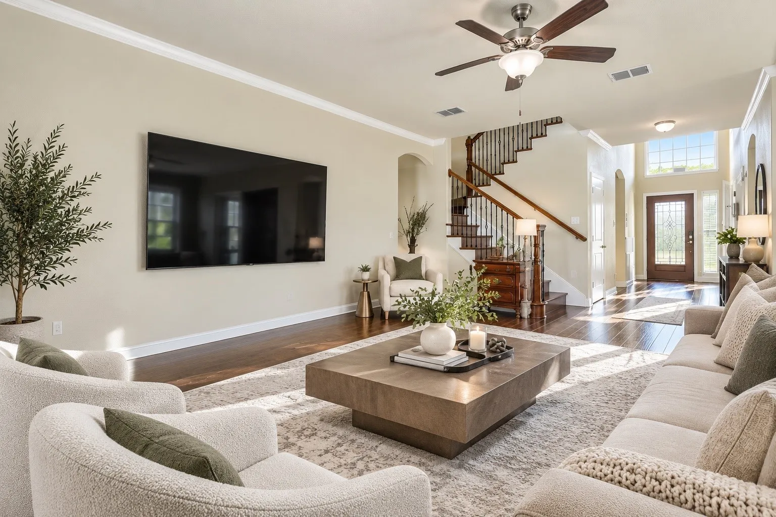 Hardwood flooring, crown molding, a built-in ceiling fan, and a two-story entryway with an arched door frame create a welcoming atmosphere