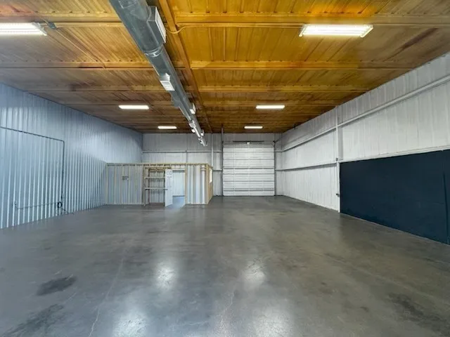 Spacious interior featuring a high wood-finish ceiling with exposed ductwork and fluorescent lighting