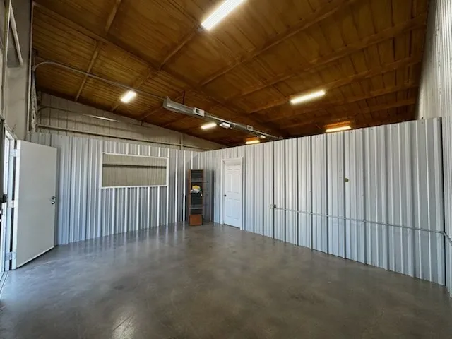 Spacious open-concept interior featuring a high vaulted wood ceiling, corrugated metal wall panels, and polished concrete flooring
