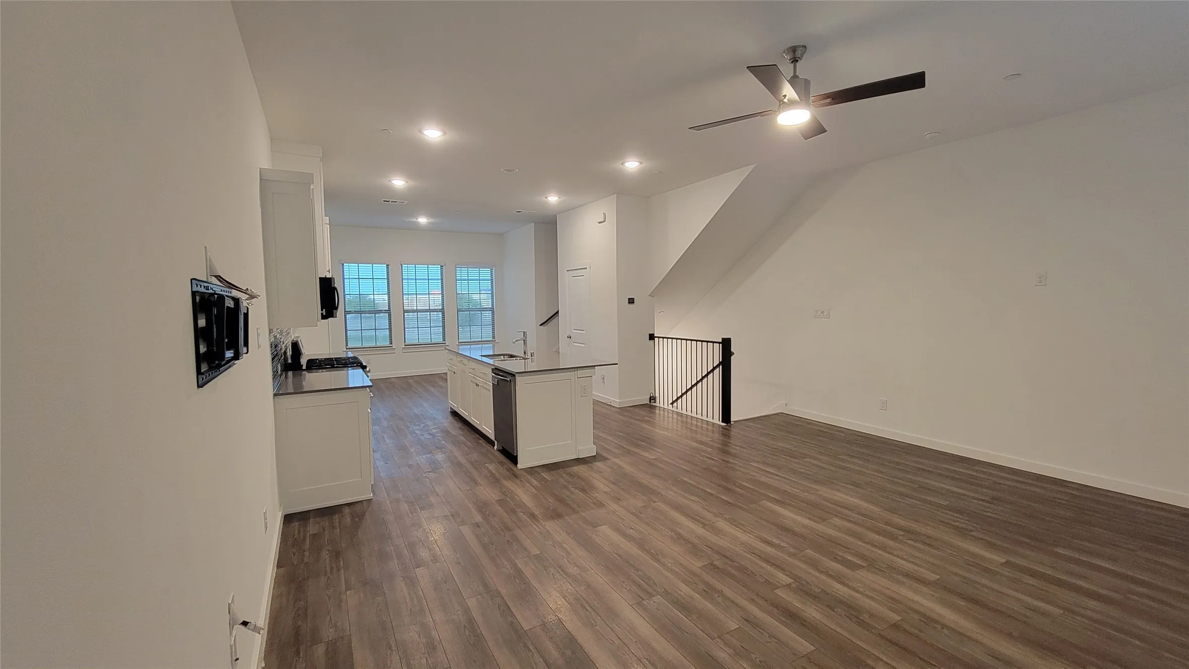 Living room featuring ceiling fan, sink, and dark wood-type flooring