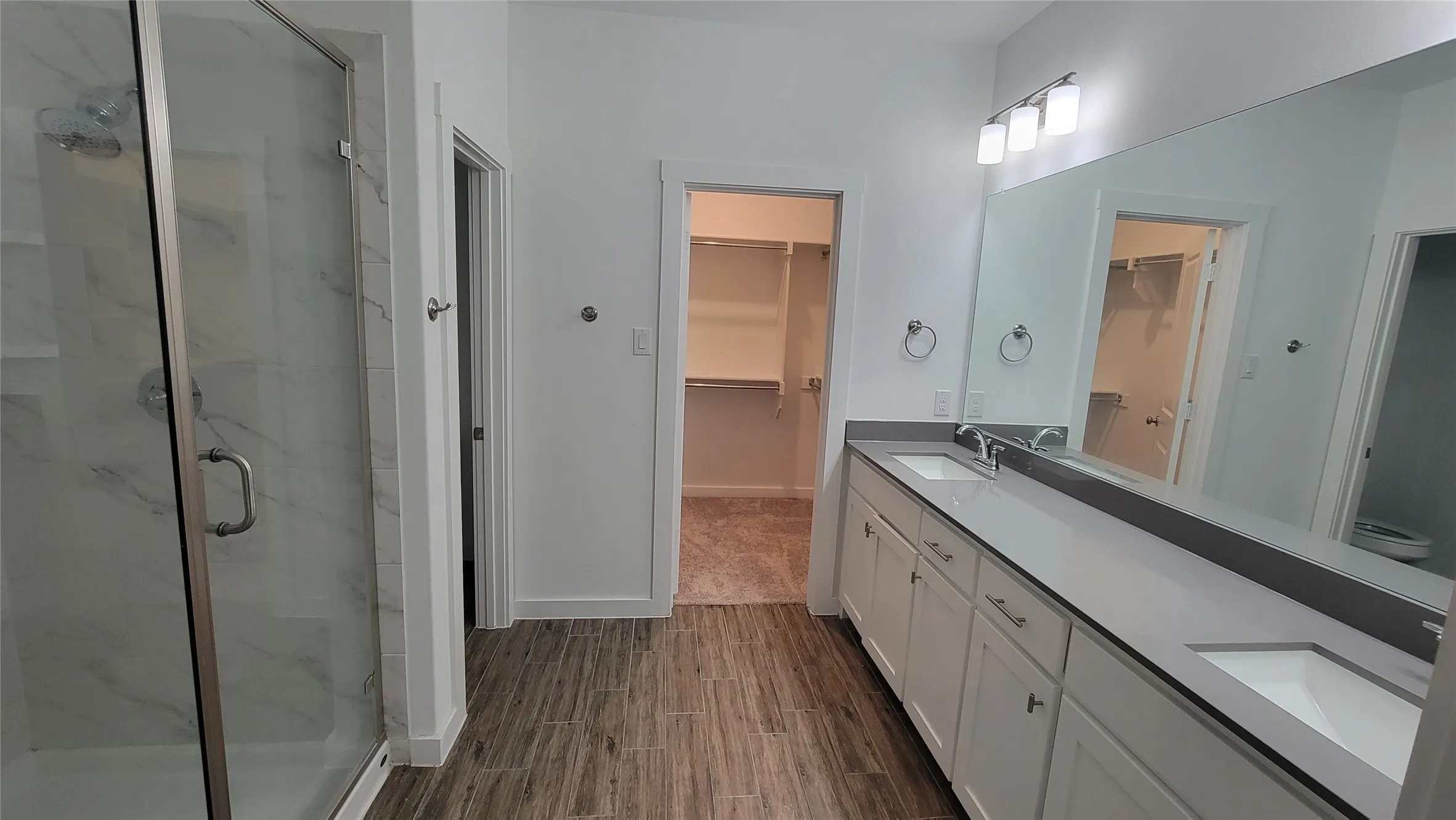 Bathroom featuring a shower with shower door, hardwood / wood-style flooring, and dual vanity