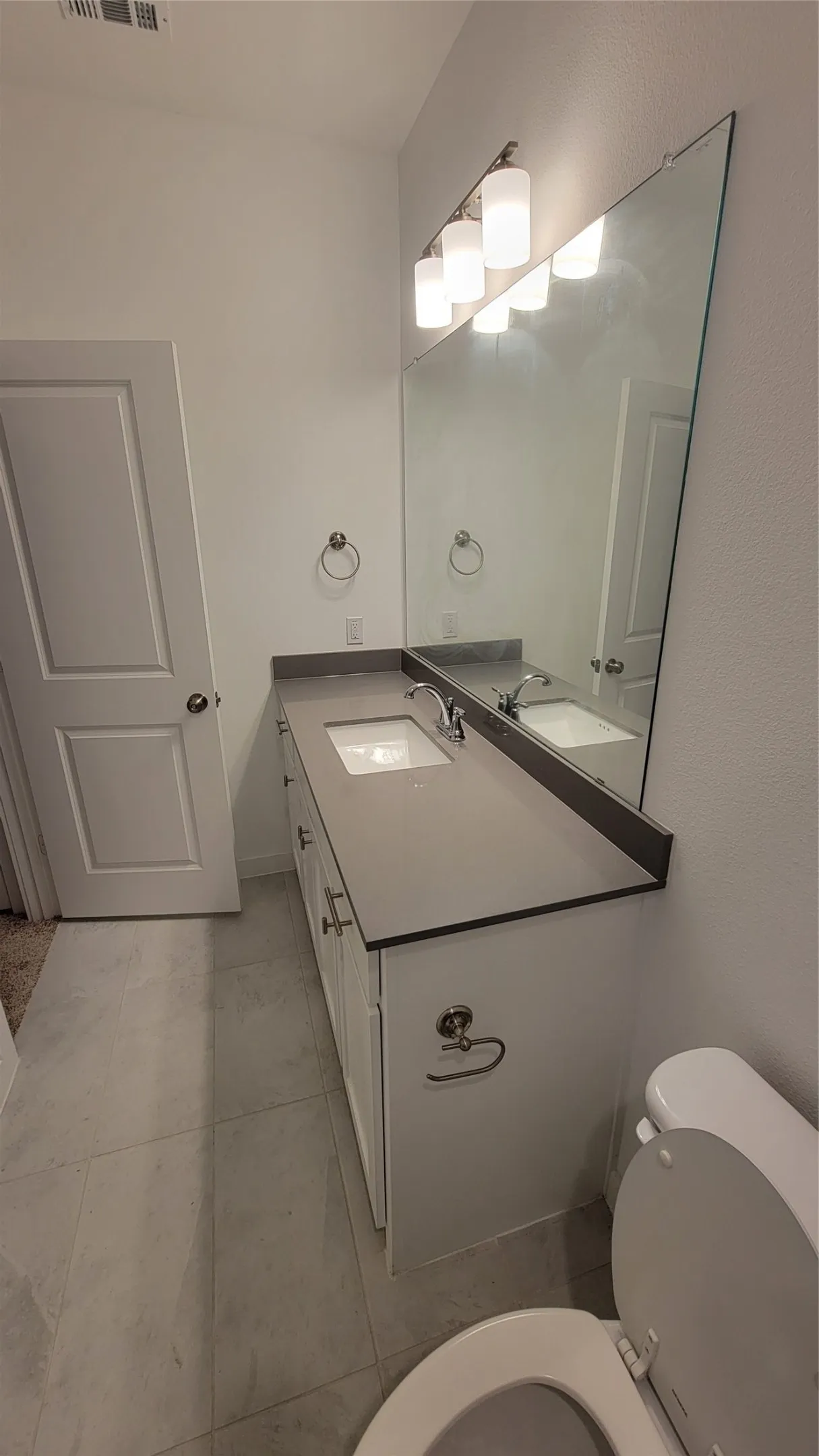 Bathroom with tile flooring, oversized vanity, and toilet
