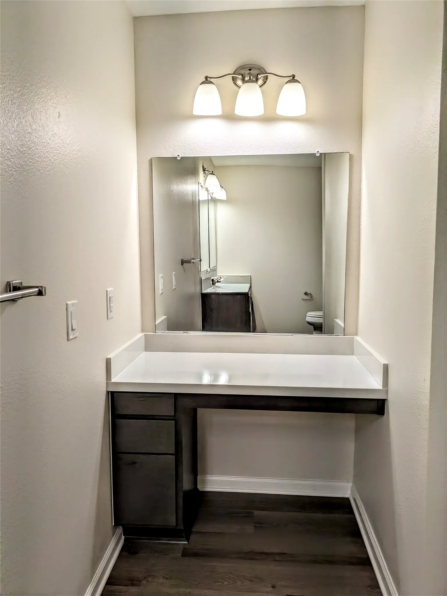 Built-in vanity with a white countertop and dark wood-finish cabinetry featuring storage drawers