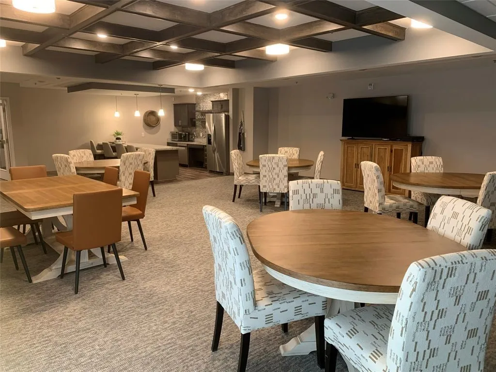 Open-concept common area featuring wood-finish ceiling beams, recessed lighting, and patterned carpeting