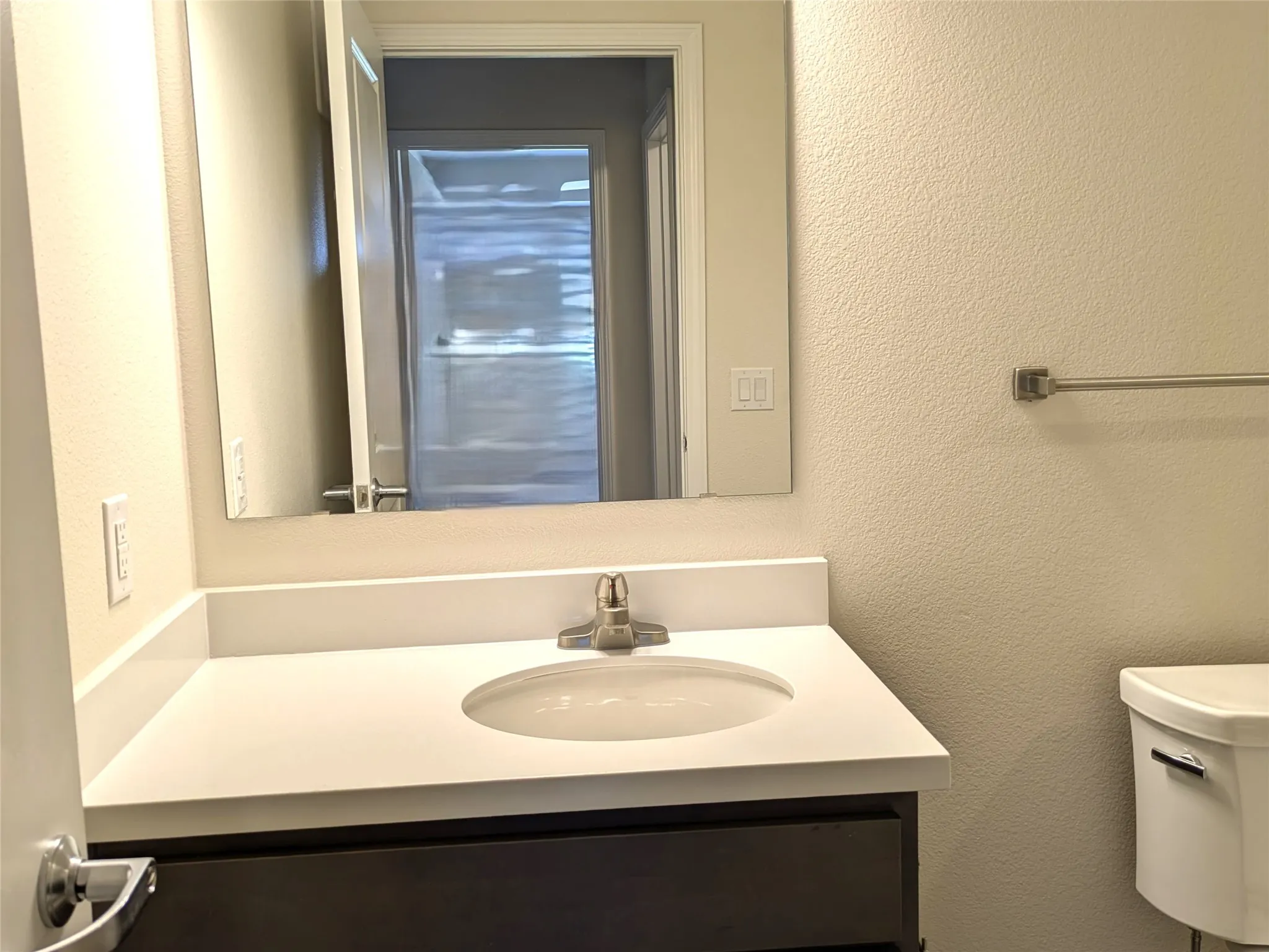 Bathroom vanity featuring a single basin sink set into a white countertop