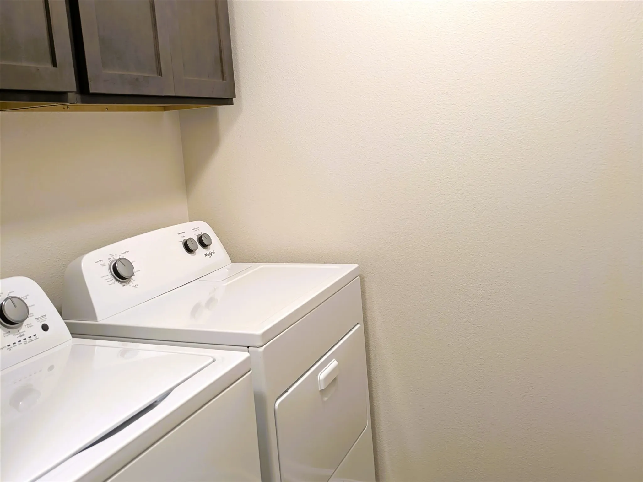 Laundry area with dark wood-finish cabinetry and light-colored walls