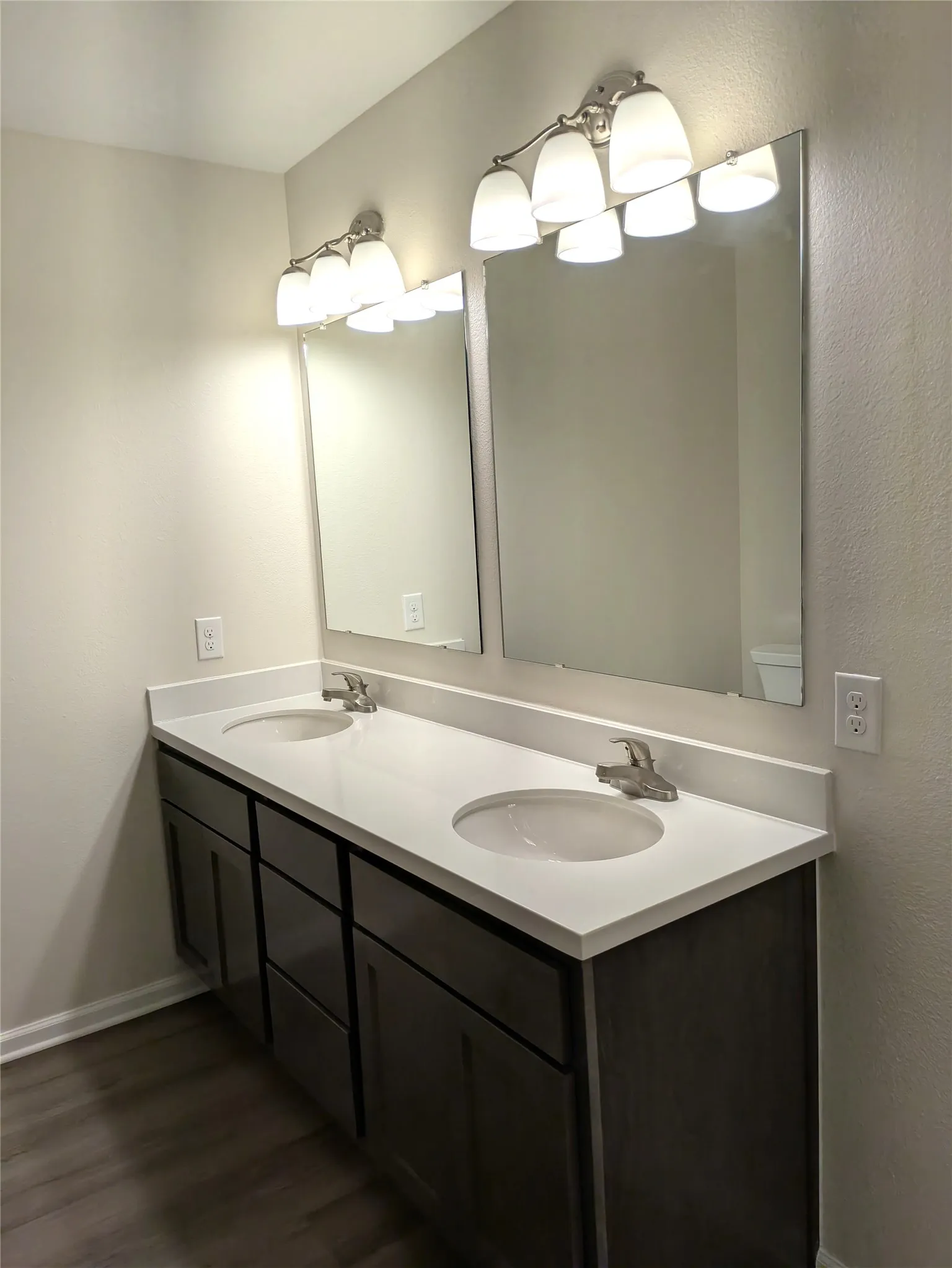 Dual sink vanity featuring a light-toned countertop, wood-finish cabinetry, and brushed nickel fixtures