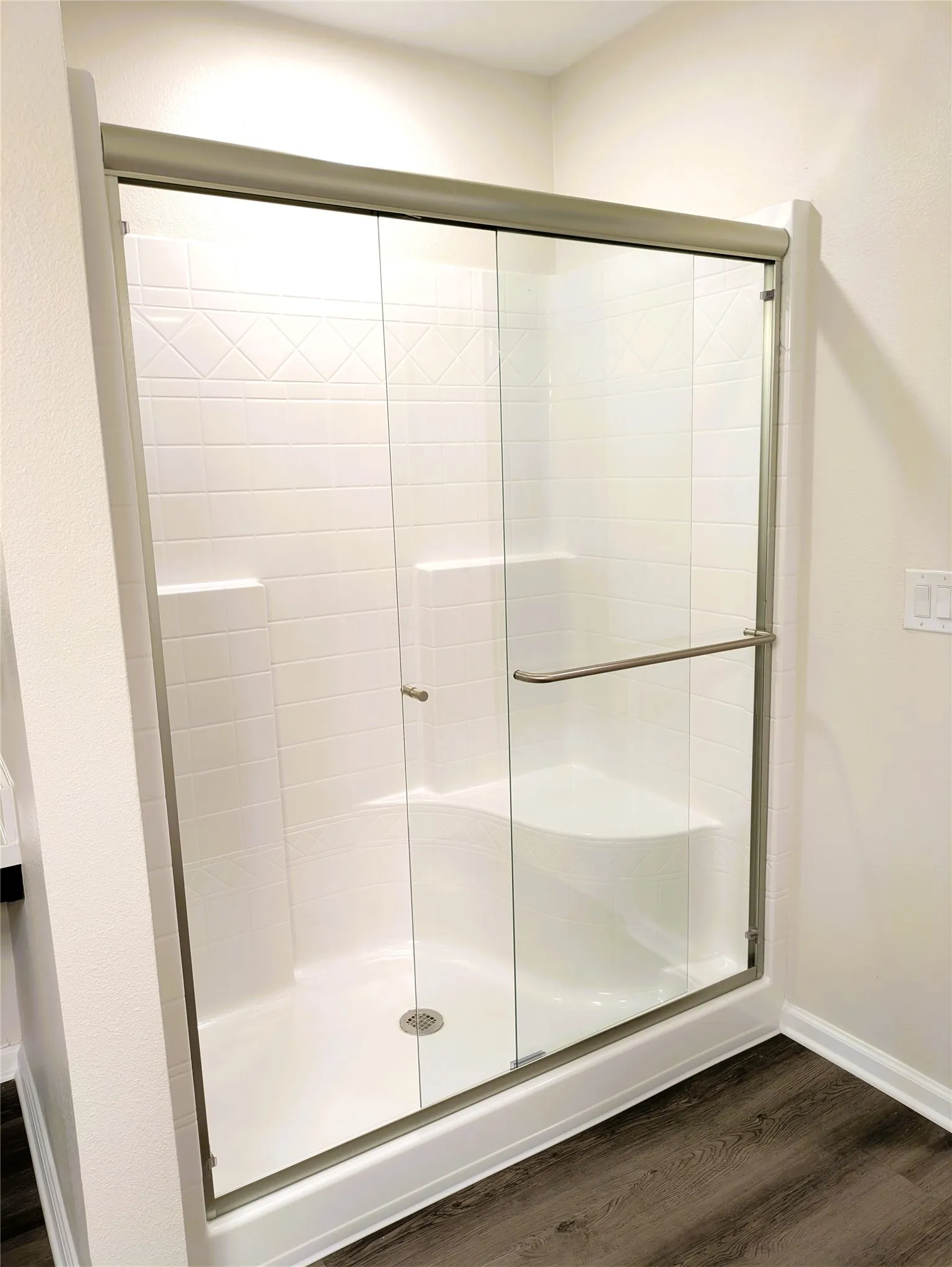 Shower enclosure featuring glass sliding doors with brushed metal hardware