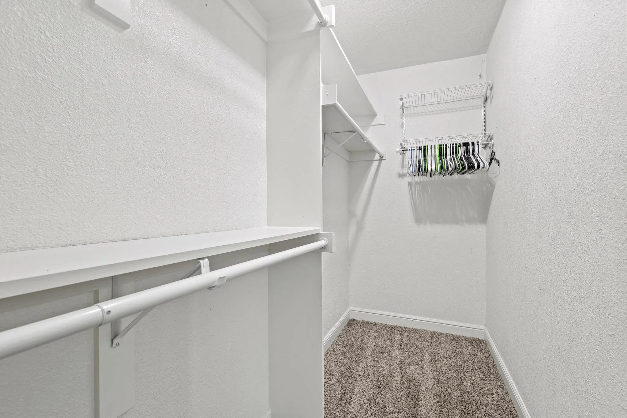 Walk-in closet featuring white wire shelving and hanging rods