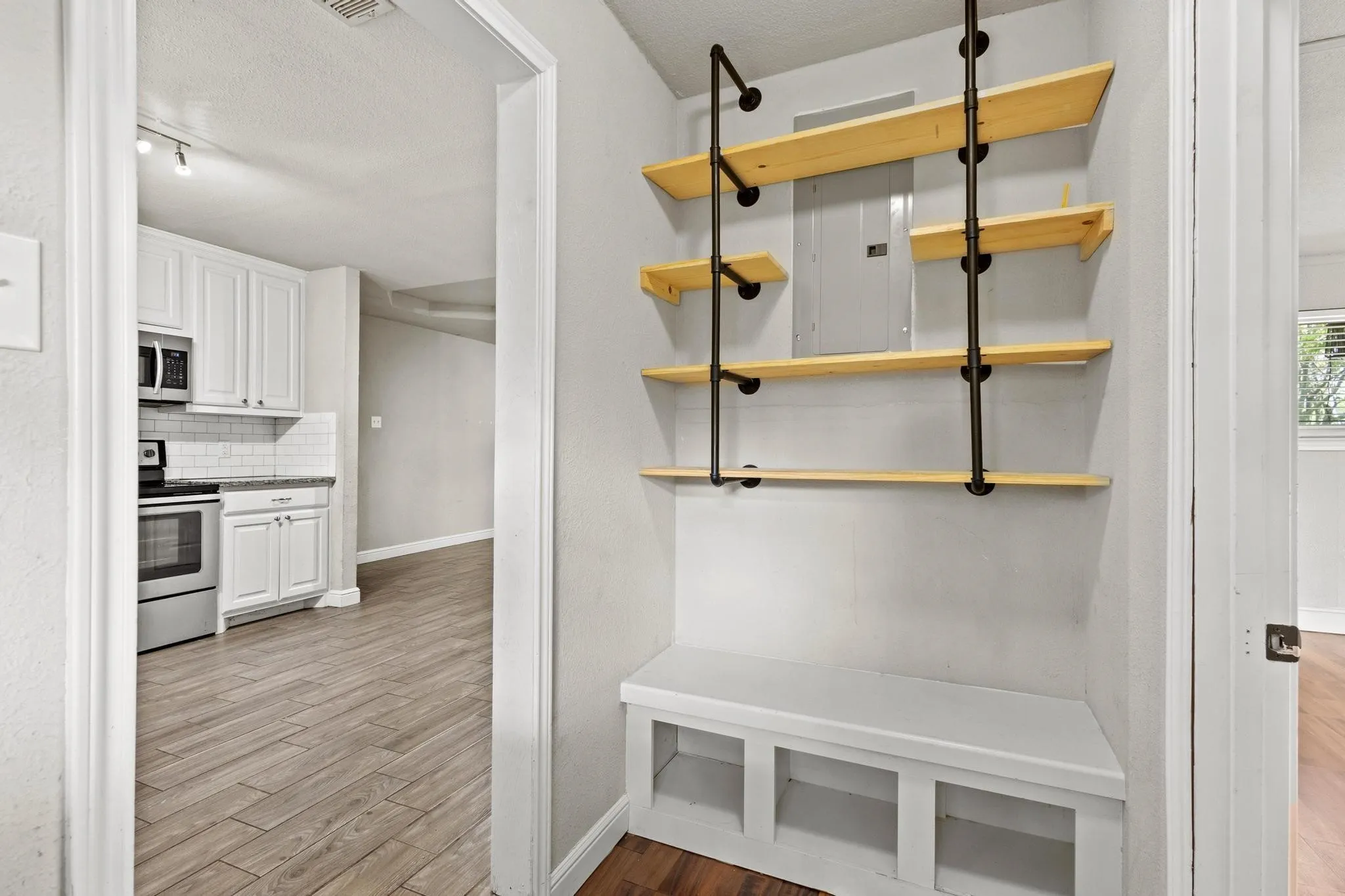 Entryway featuring custom industrial-style shelving with light wood shelves and a built-in bench