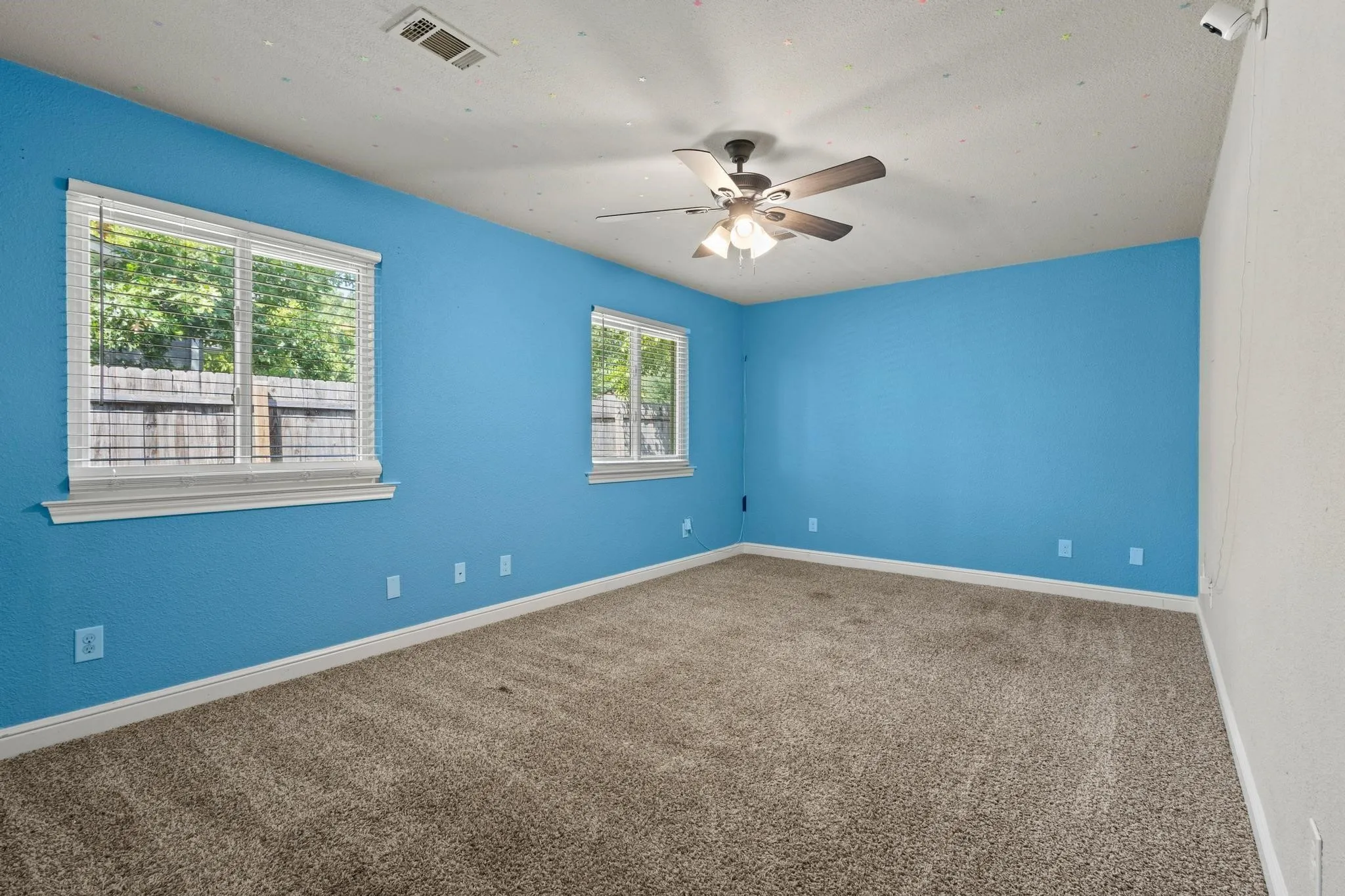 Carpeted room featuring multiple windows, a ceiling fan with integrated lighting, and painted walls. Carpet replaced 08-12-2026.