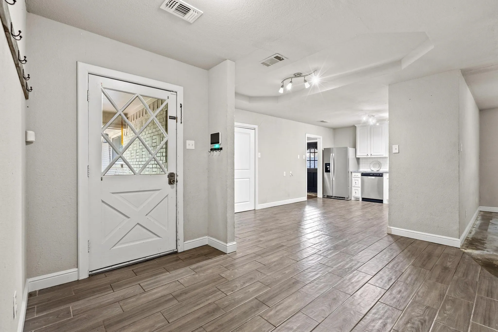 Entryway with a white paneled door featuring diamond-patterned glass, wood-finish flooring, and recessed lighting