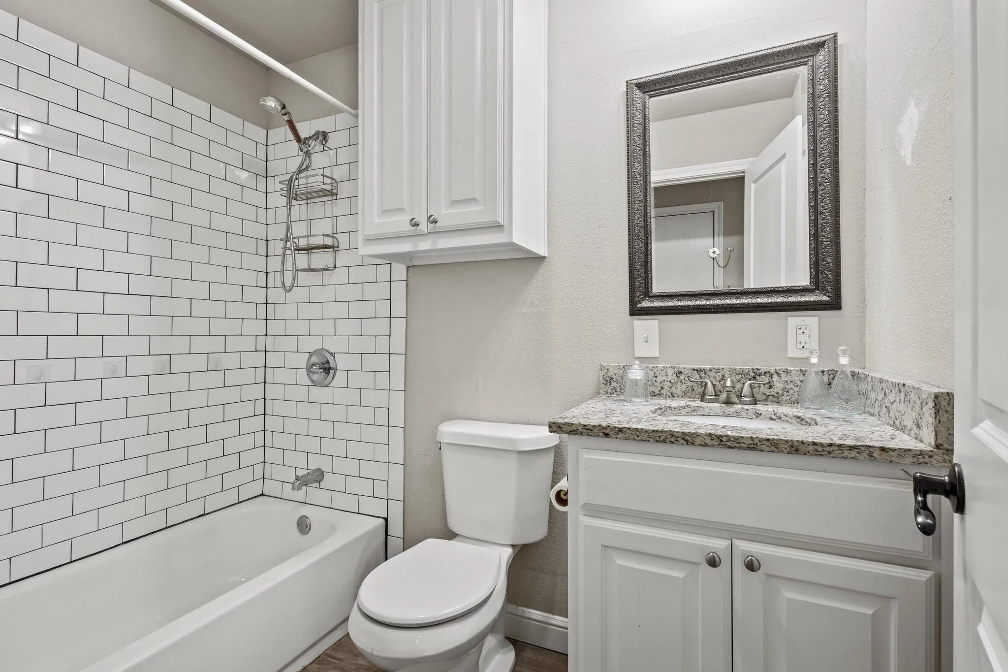 Bathroom featuring white subway tile surround, a white built-in bathtub, and a vanity with a stone countertop