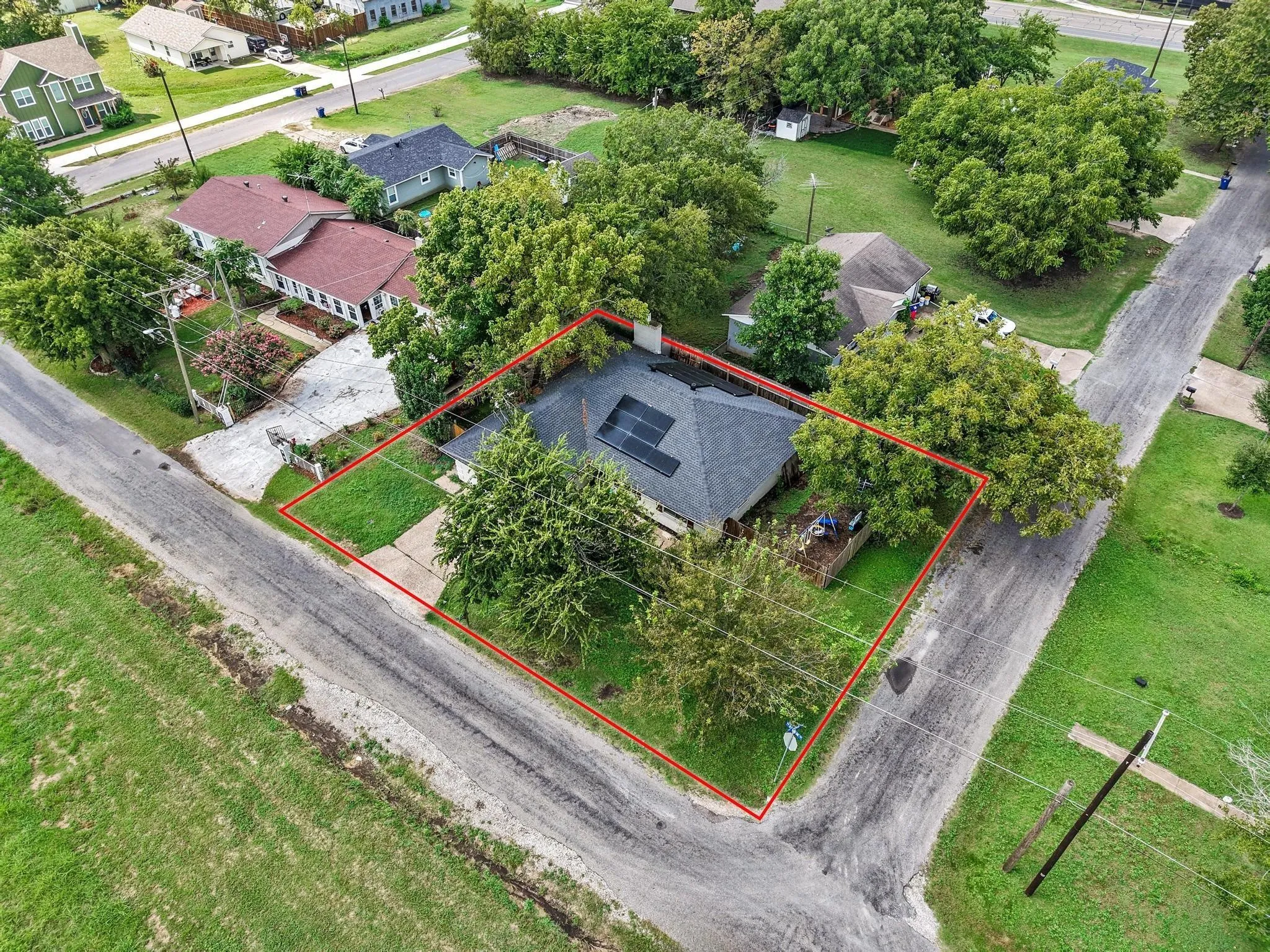 Corner lot property featuring mature trees and solar panels