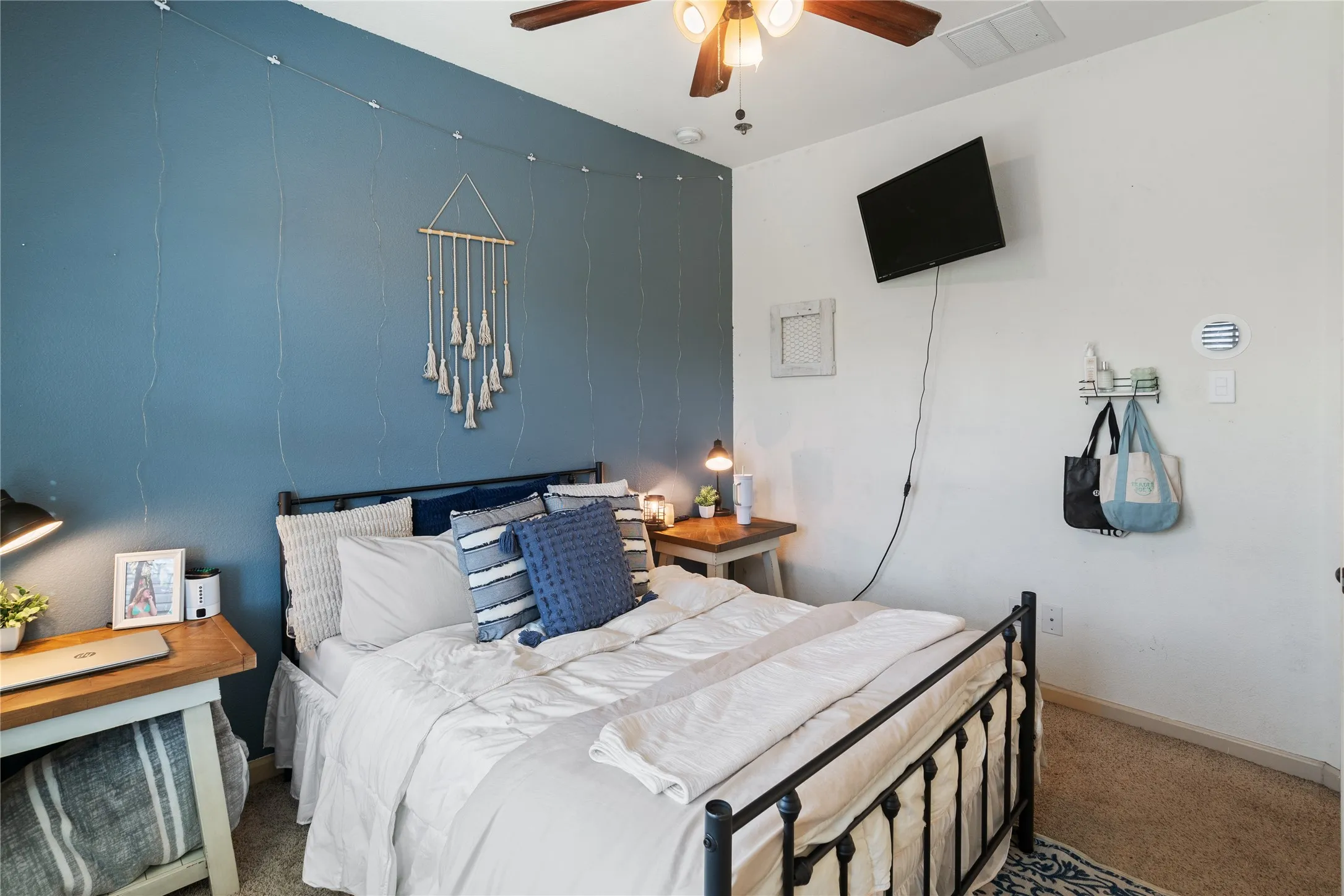 Upstairs bedroom number 3 featuring a decorative accent wall, ceiling fan, and carpeted flooring
