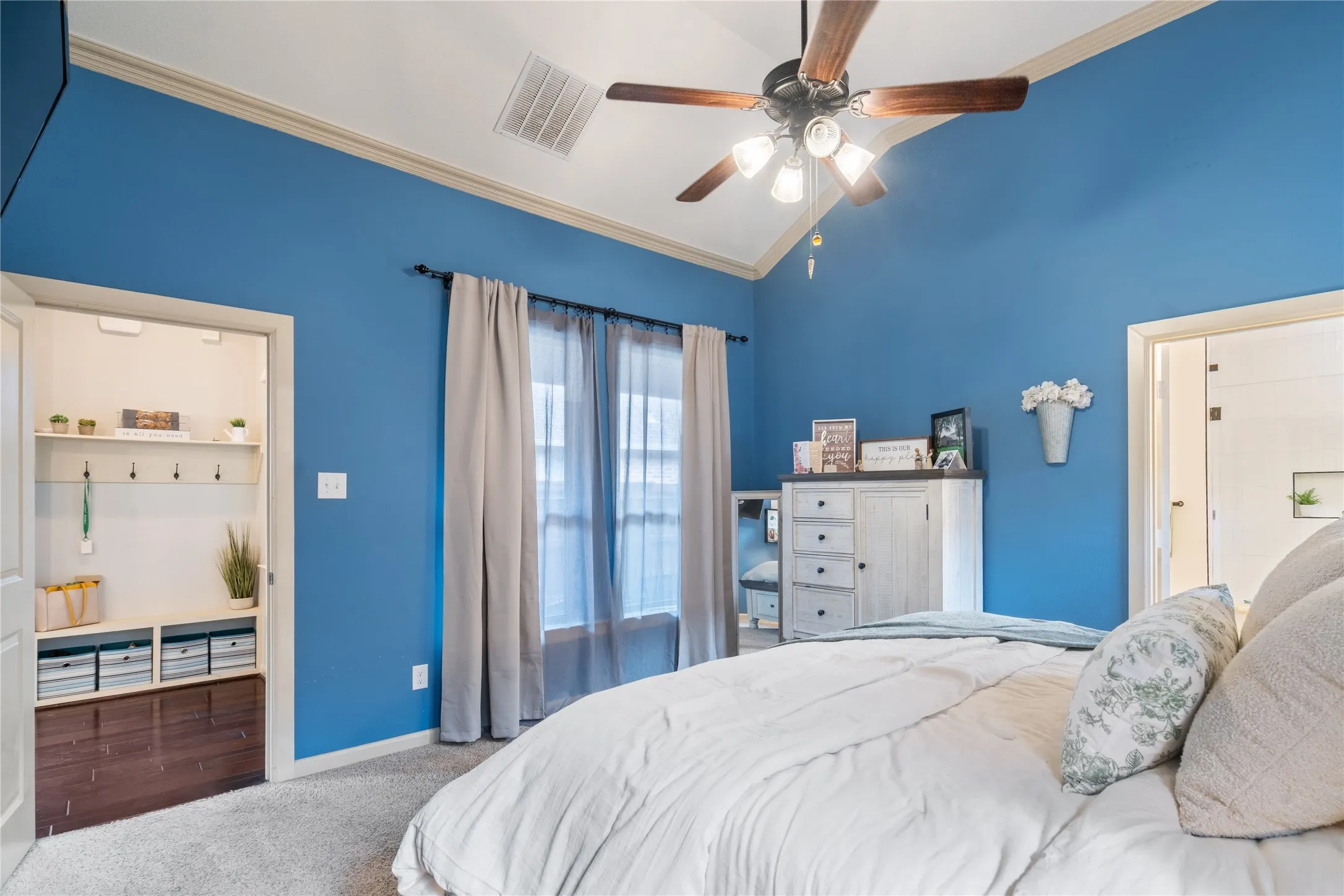 Crown molding frames this roomy primary bedroom with  vaulted ceiling and customized closets