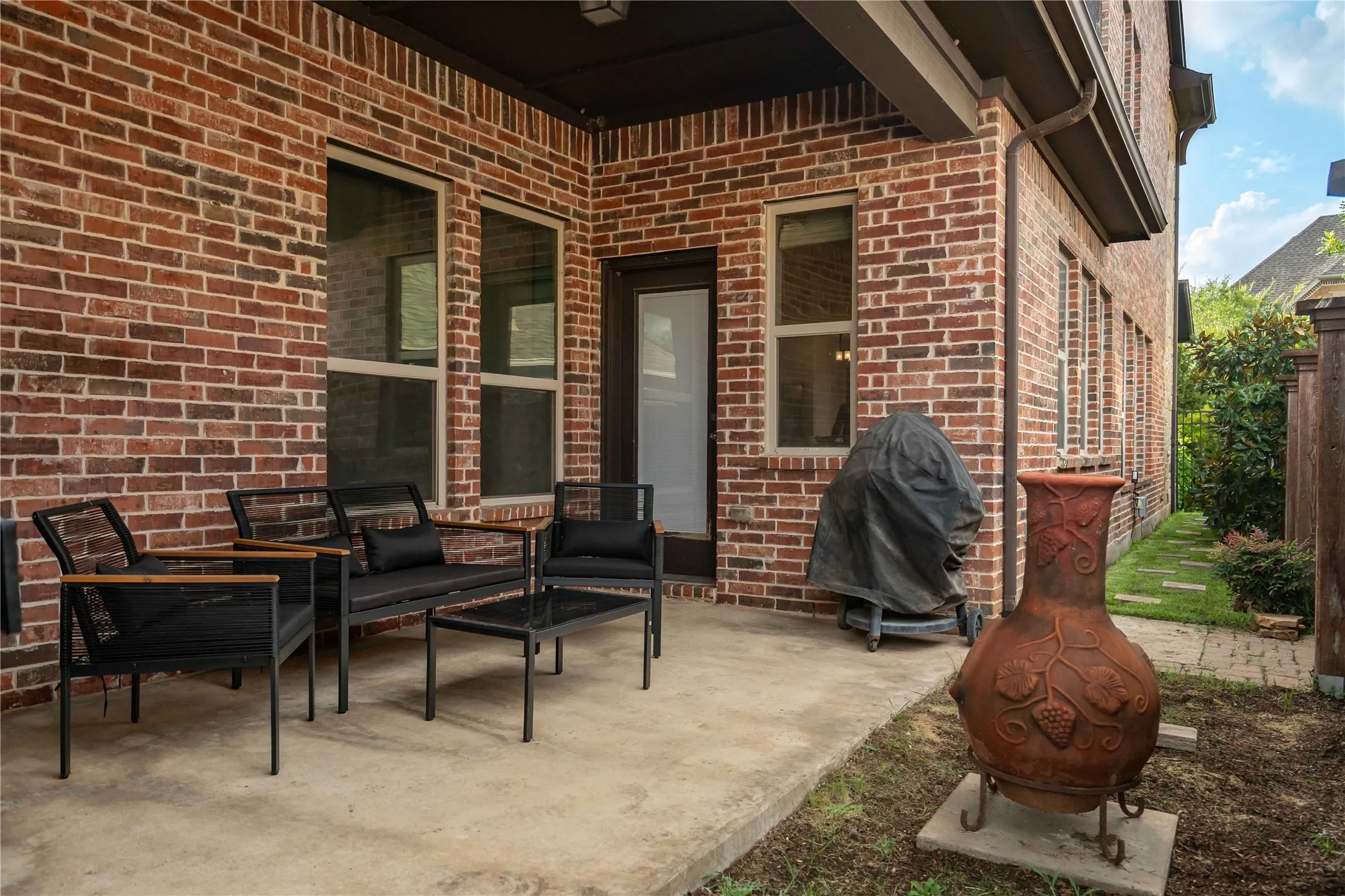 Outdoor patio with extended  concrete surface and a brick exterior