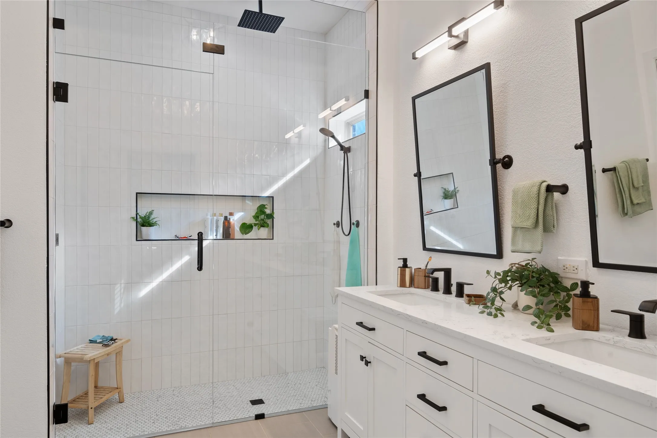 Contemporary bathroom featuring a glass-enclosed shower with vertical tile, a built-in shower niche, and a voice activated black rain shower head