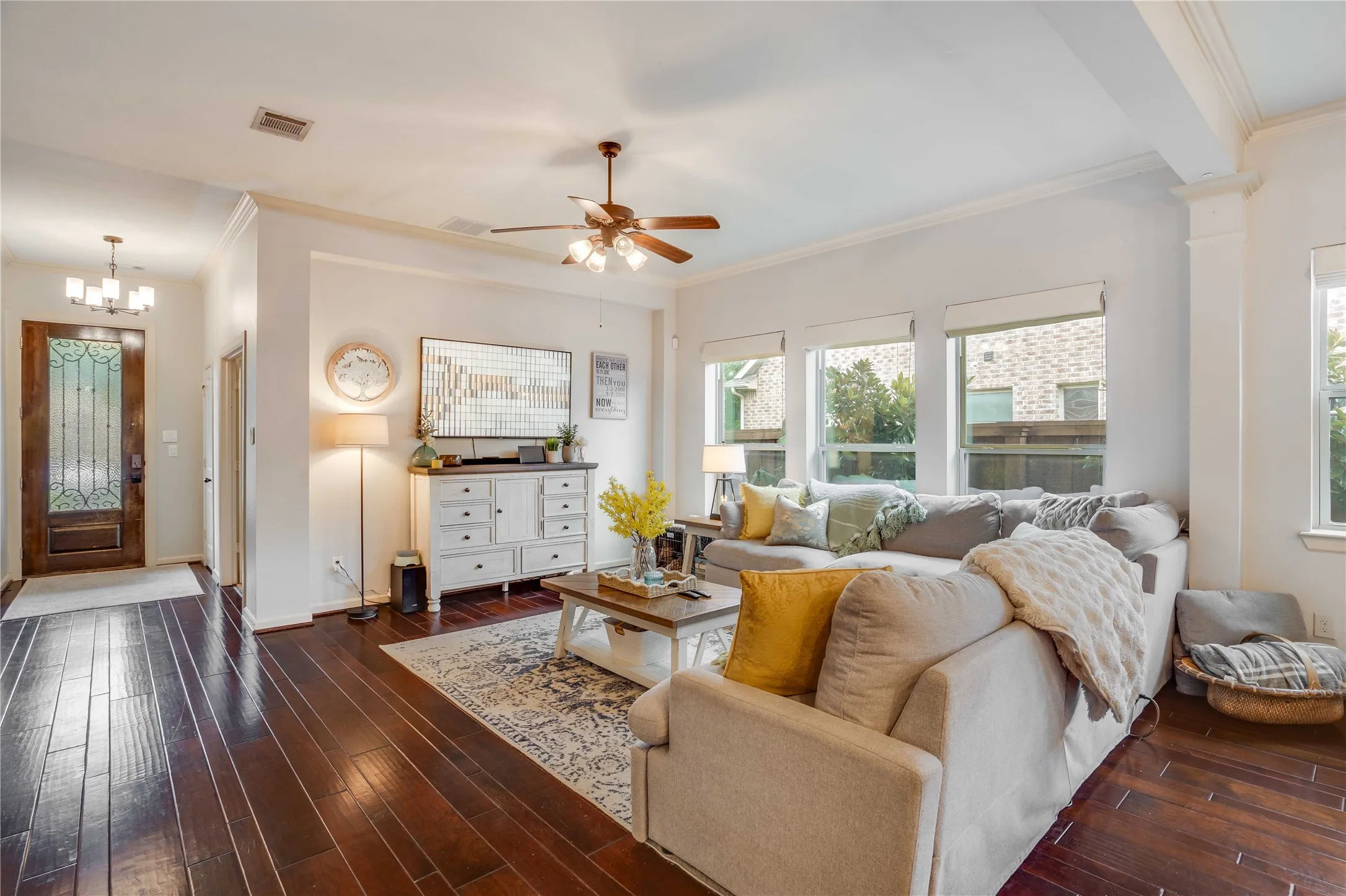 Mahogany wood flooring with a designer wood and metal entrance door framed by the light walls and crown molding is both inviting and relaxing.