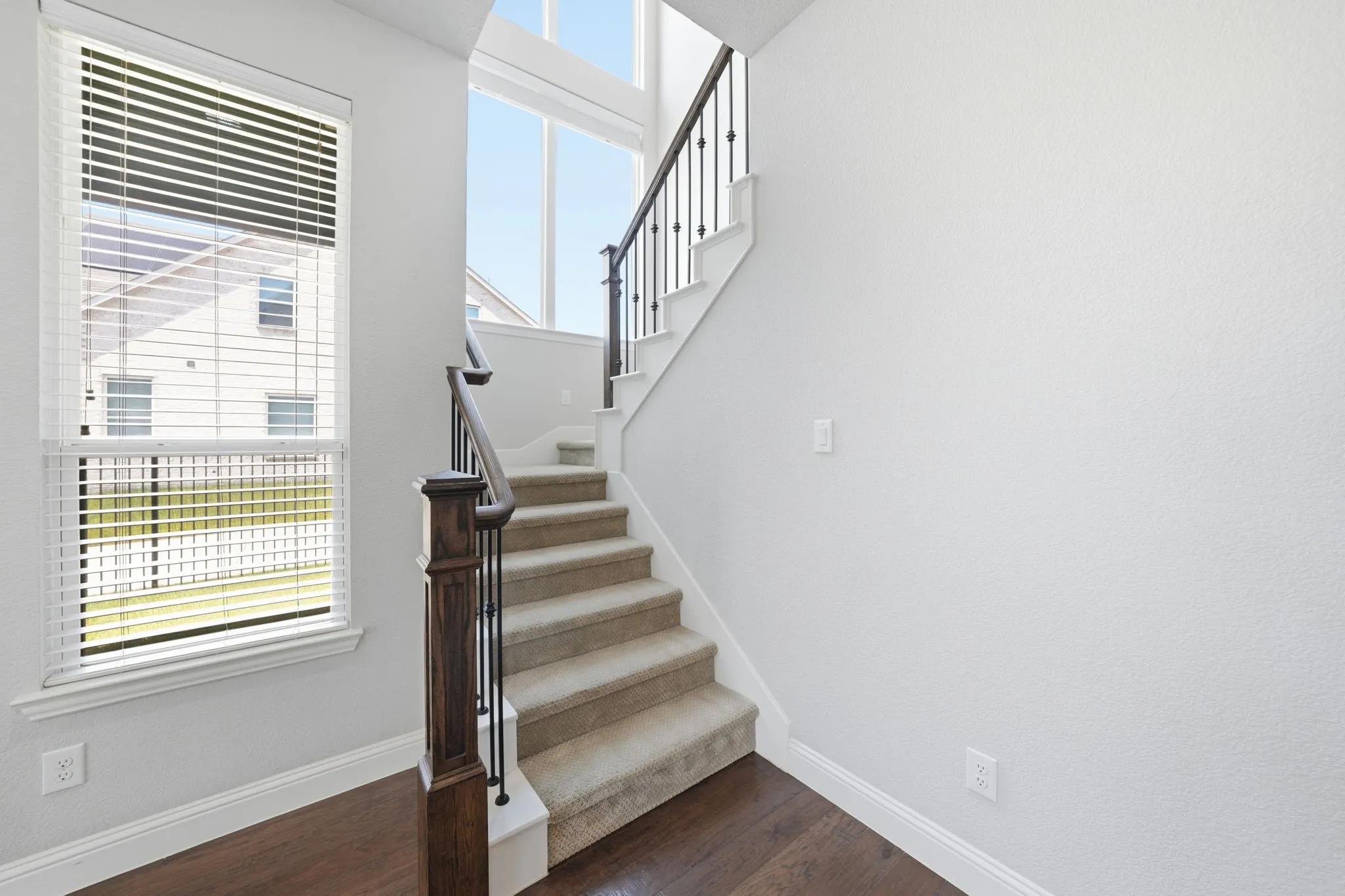 Staircase featuring dark wood newel posts and handrails with black metal balusters