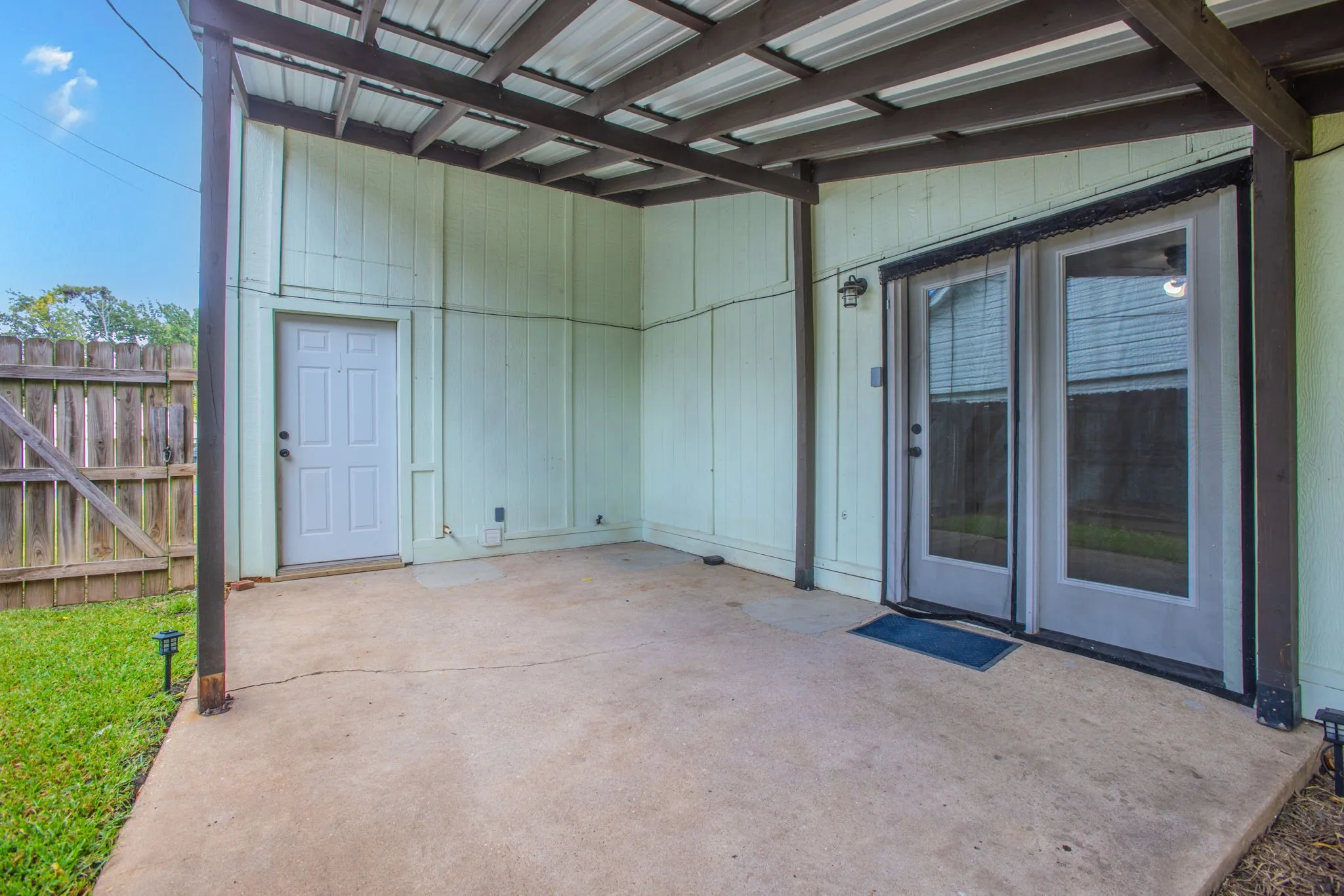 Covered patio with a corrugated metal roof, providing an outdoor living area