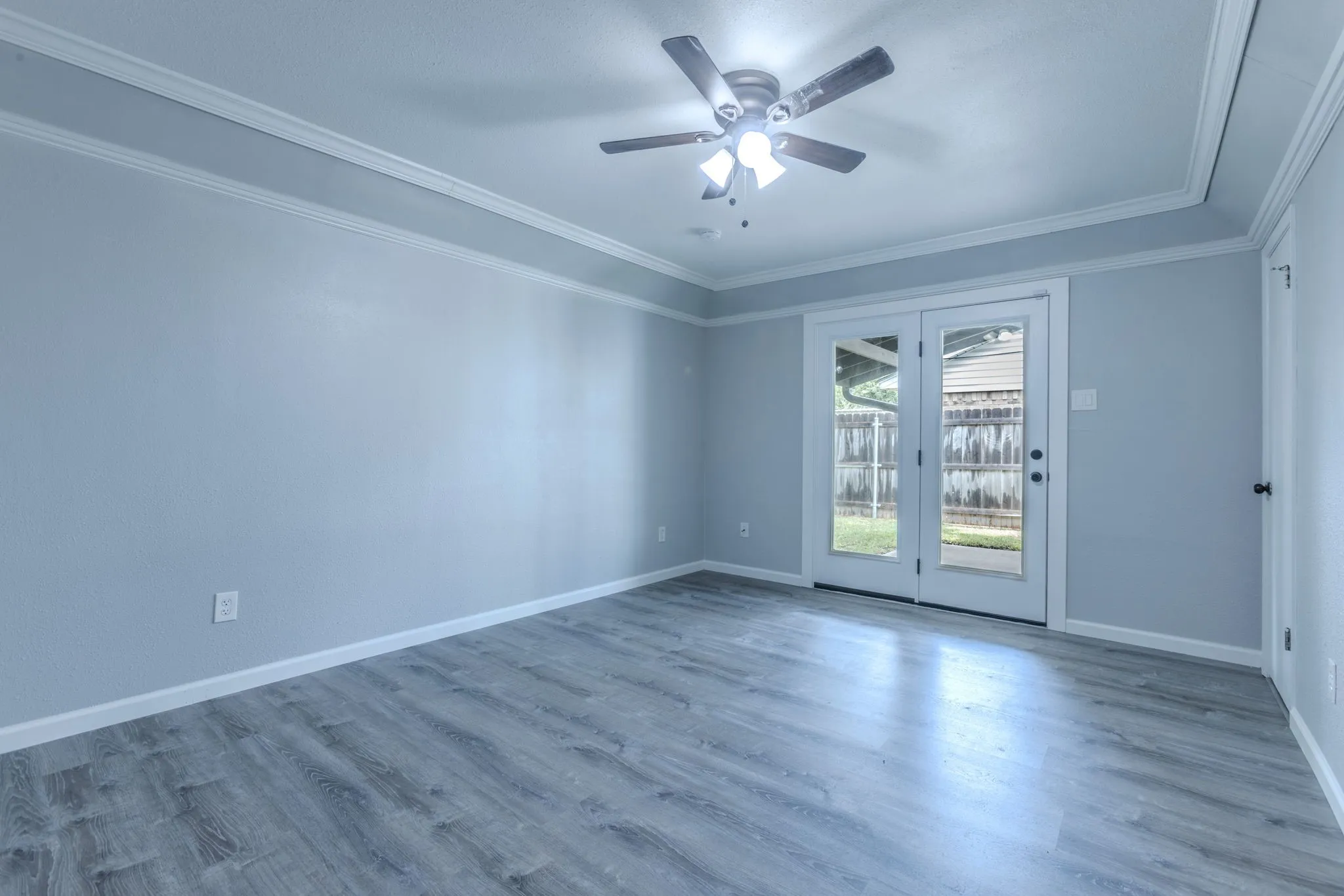 Room featuring wood-finish flooring, crown molding, and a ceiling fan