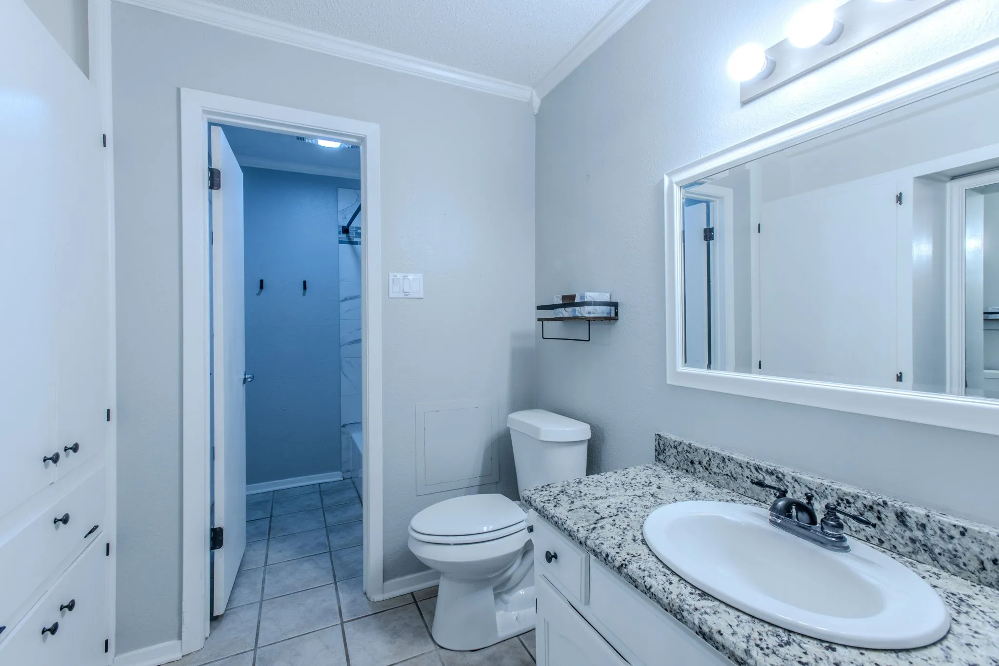 Bathroom featuring a white vanity with granite-finish countertop, undermount sink, and framed mirror