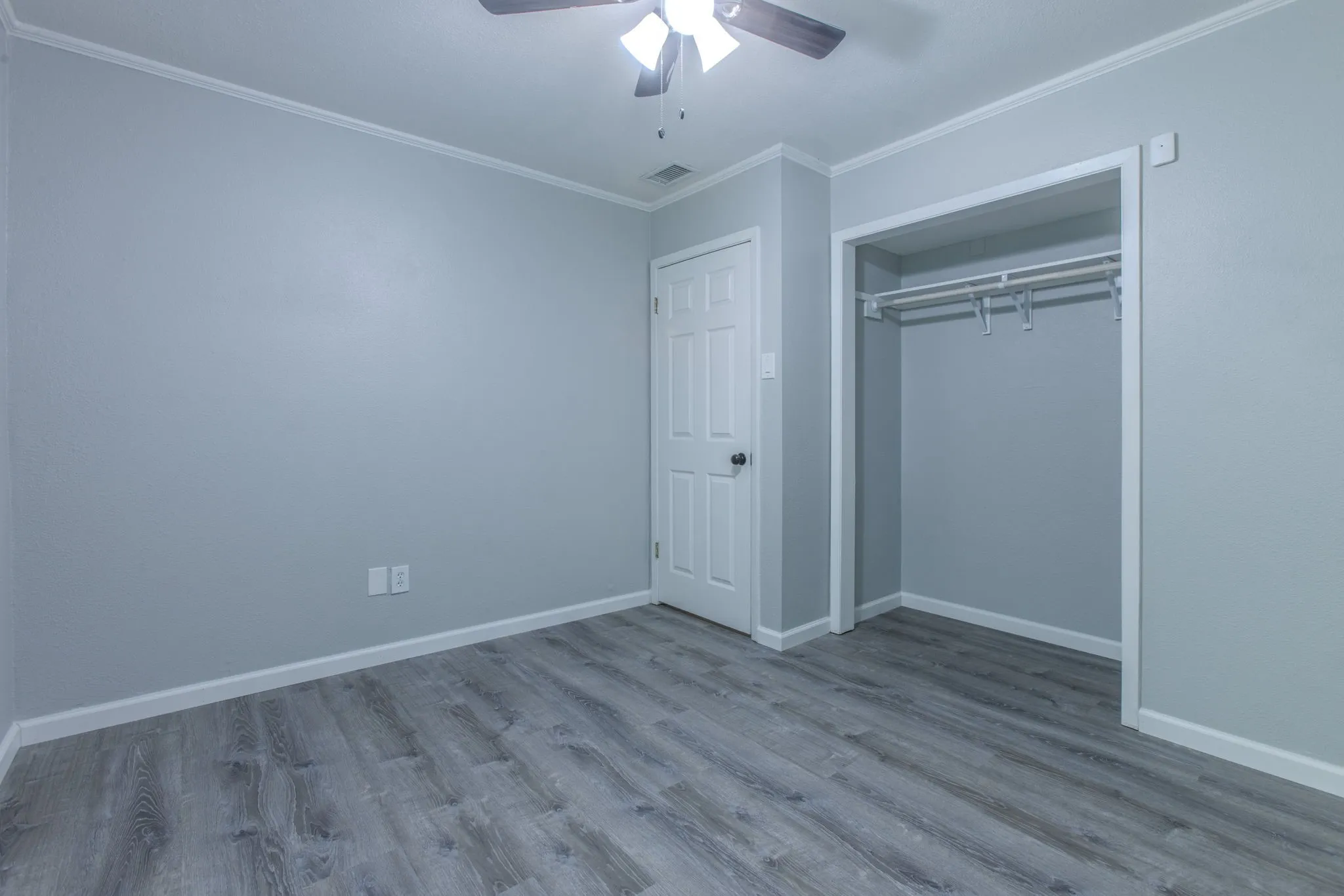Room featuring grey wood-finish flooring, light grey walls, and white trim