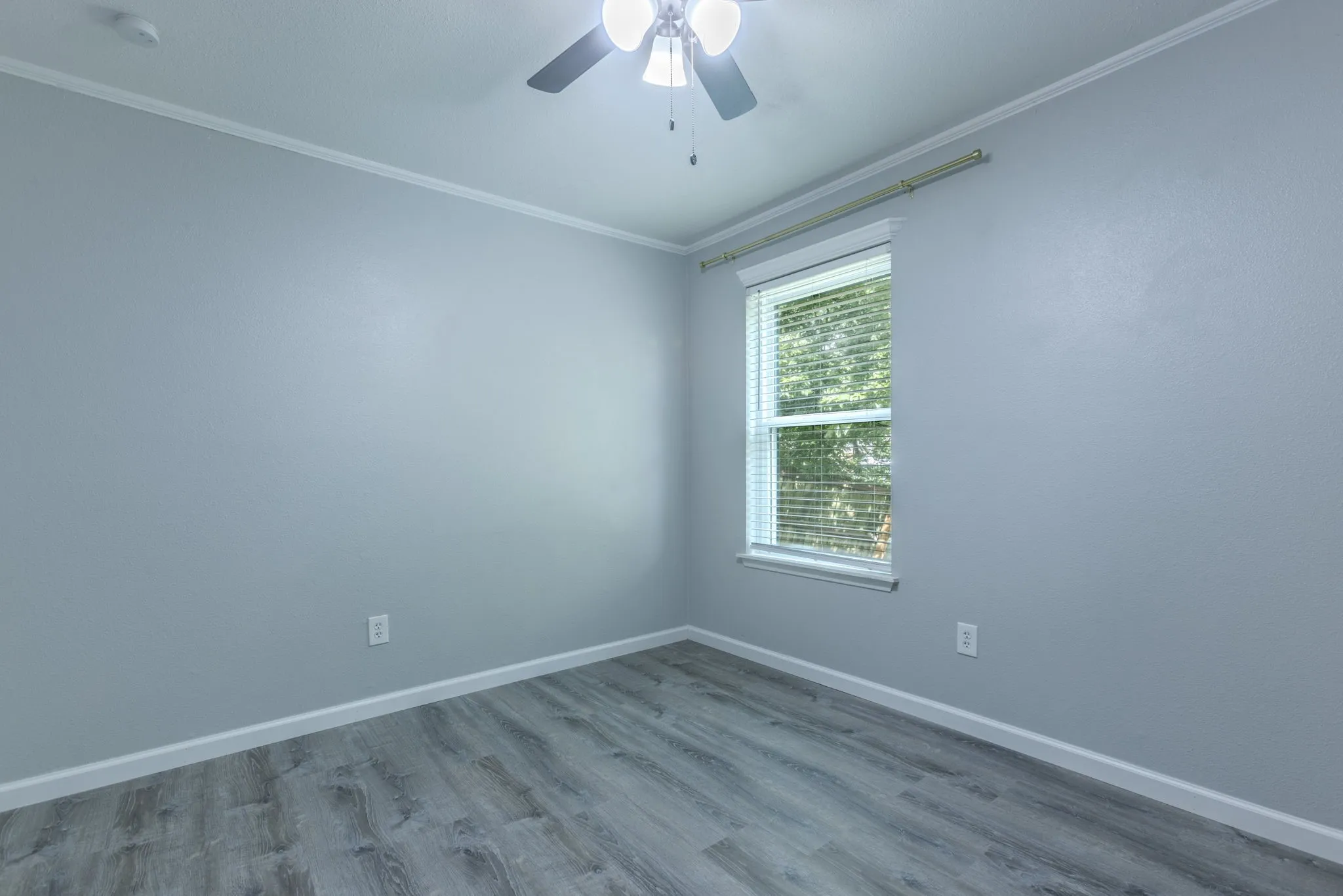 Neutral-toned interior with wood-finish flooring, a ceiling fan with light fixture, and window blinds