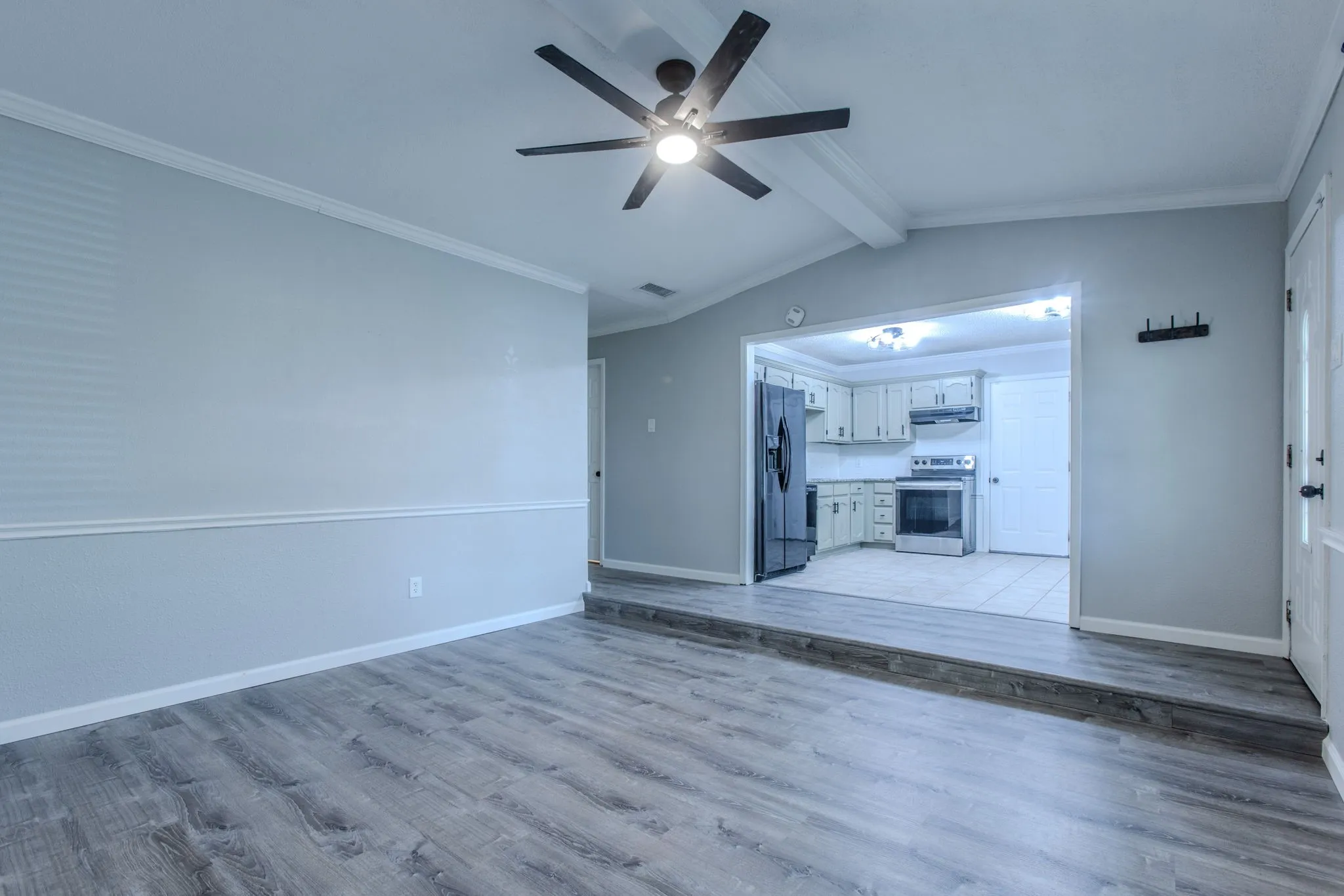 Spacious living area featuring wood-finish flooring, crown molding, and a ceiling fan