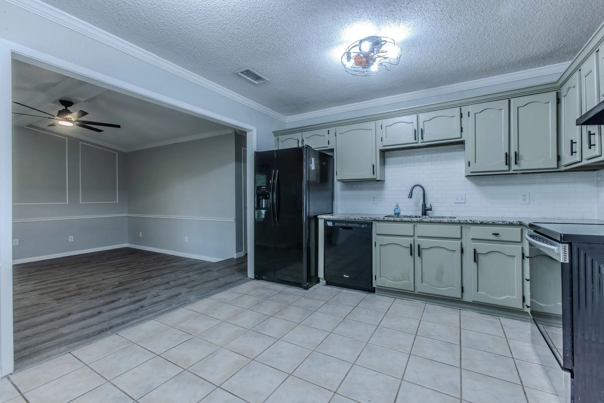 Kitchen featuring light gray cabinetry, black appliances, white subway tile backsplash, and granite-style countertops