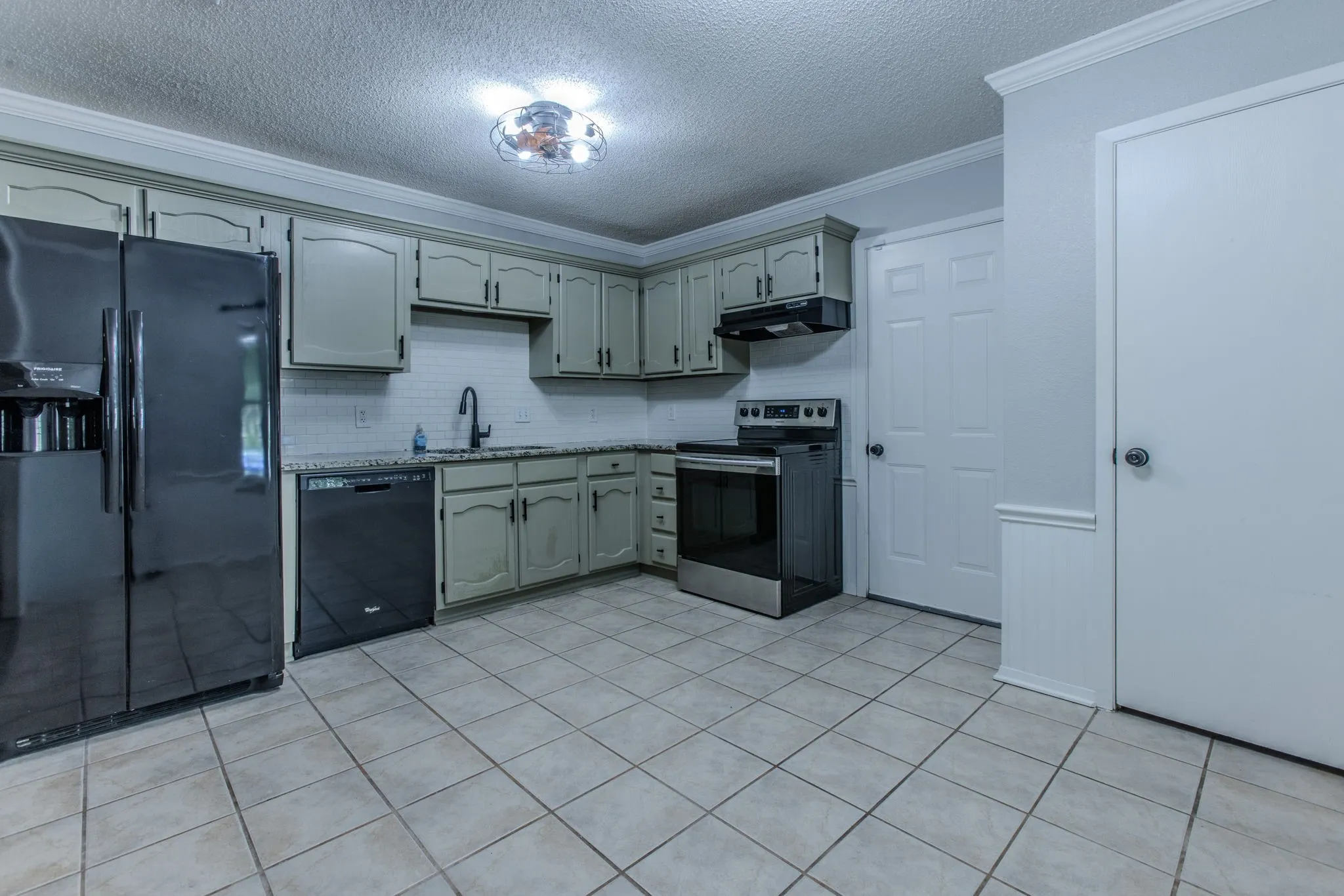 Kitchen featuring light green cabinetry, tile backsplash, and granite-style countertops