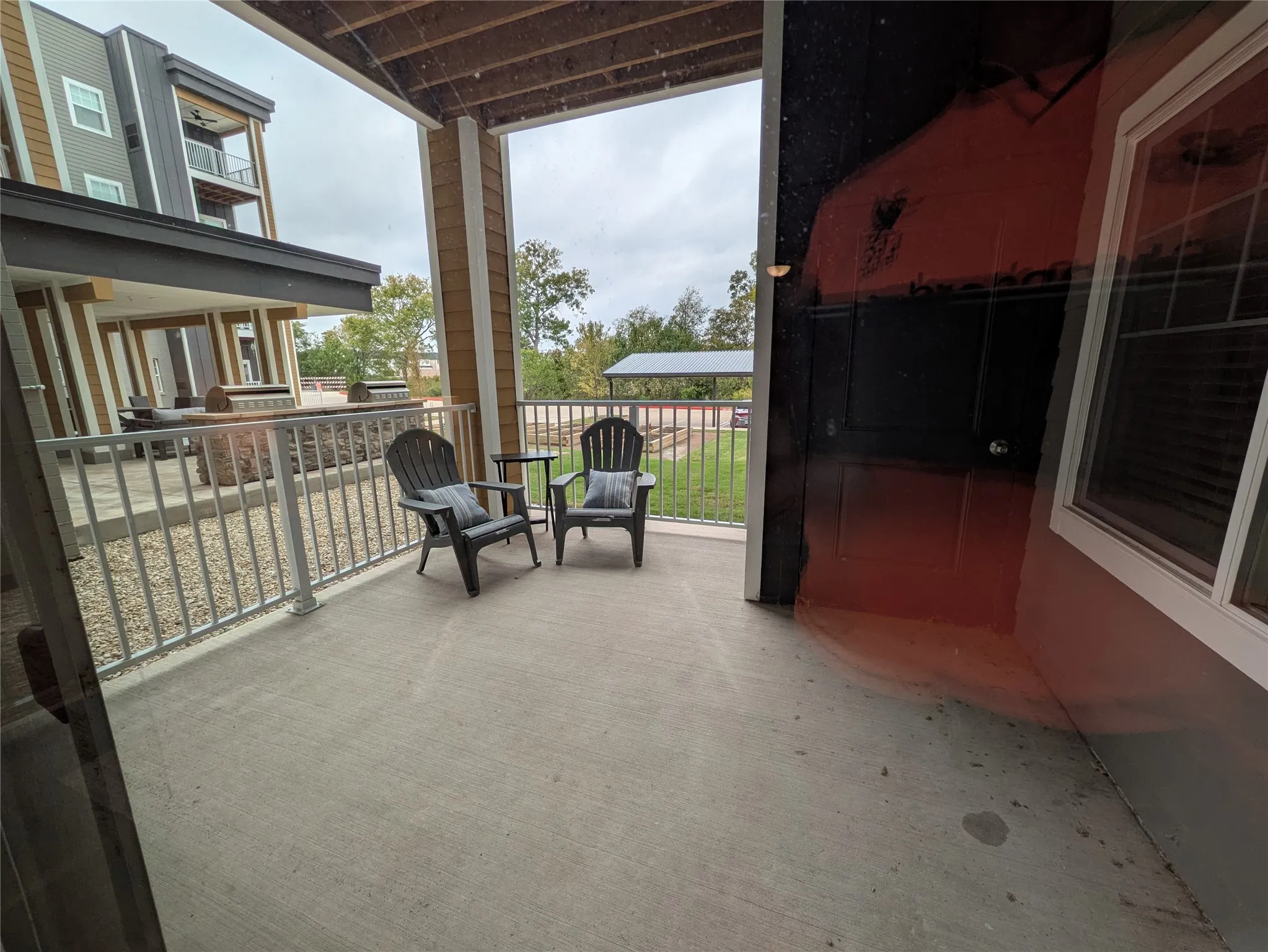 Private patio space with concrete flooring, framed by structural columns and a white railing